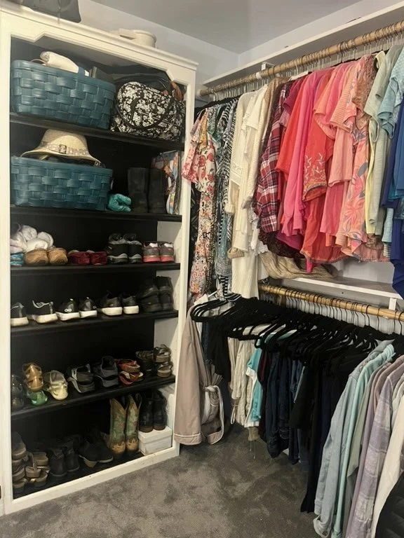 Closet with shelves of shoes, hats, and bags on the left, and racks of clothing including shirts, dresses, and pants hanging on rods on the right.