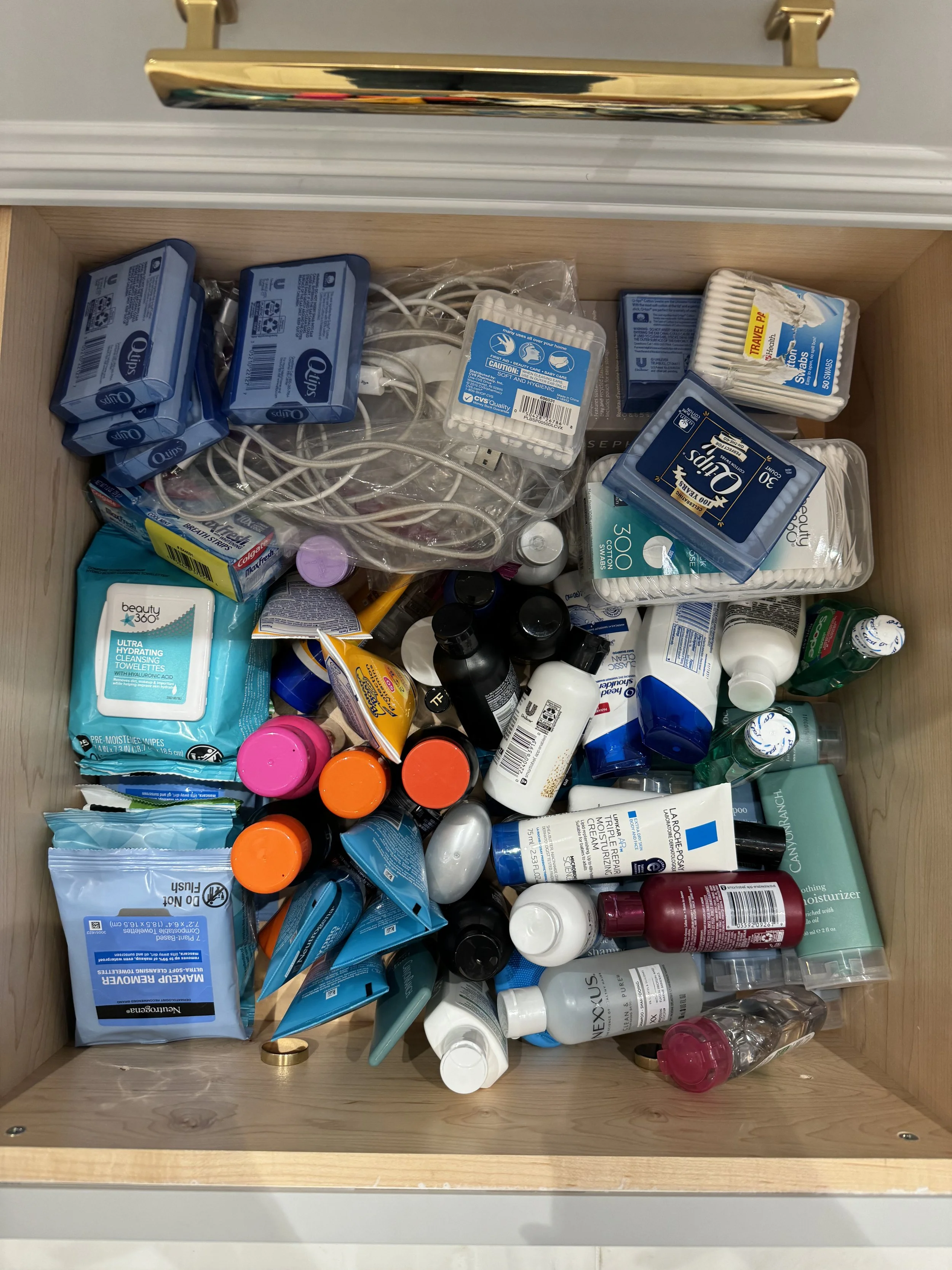 Open drawer filled with skincare, hygiene, and personal care products, including wipes, lotions, sprays, and containers.