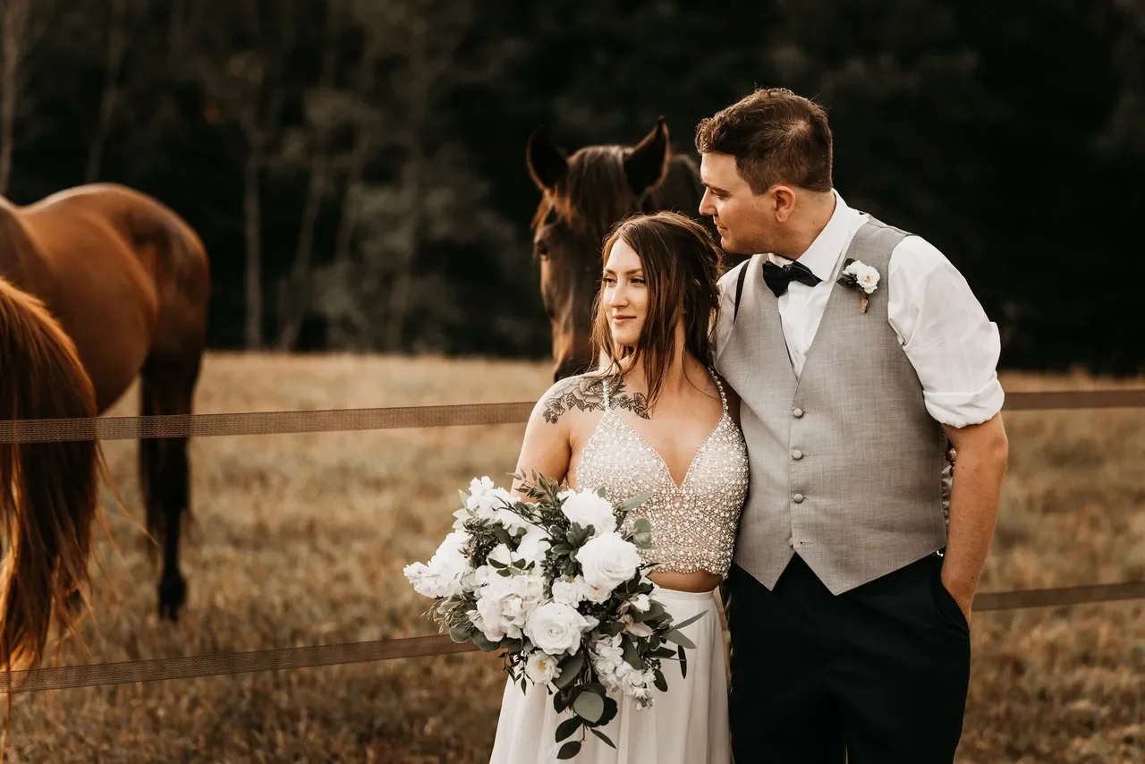 Bride and groom gazing out into a field full of horses.