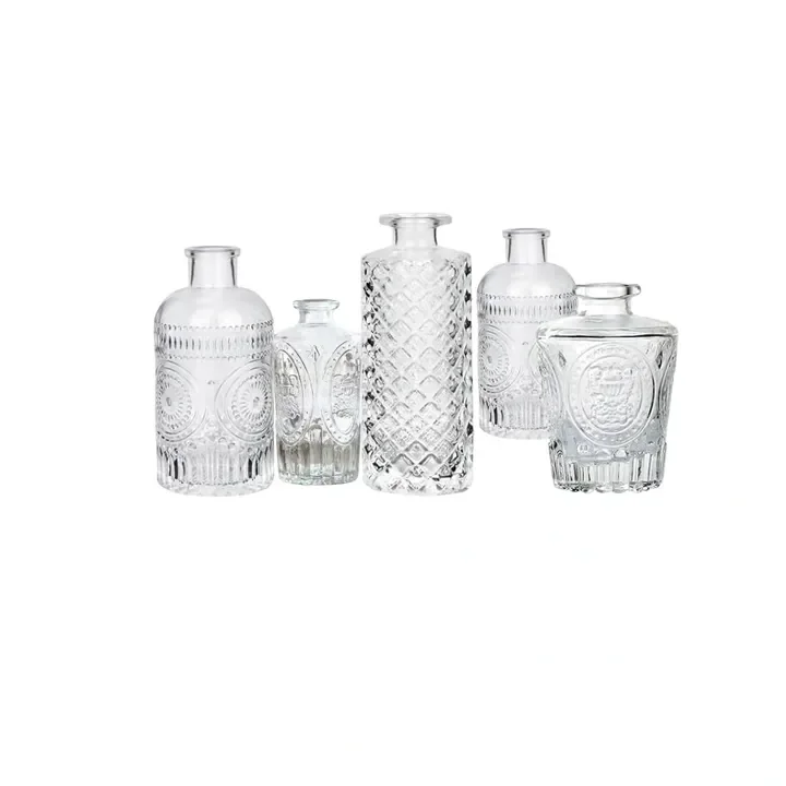Six clear glass vases with intricate patterns and varying shapes, set against a plain white background.