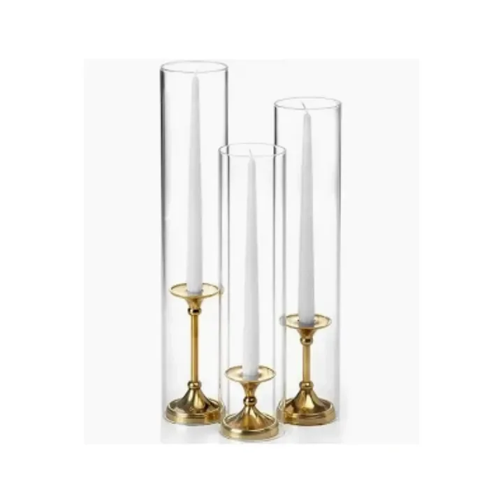 Three tall glass candle holders with gold bases, each containing a white candle.