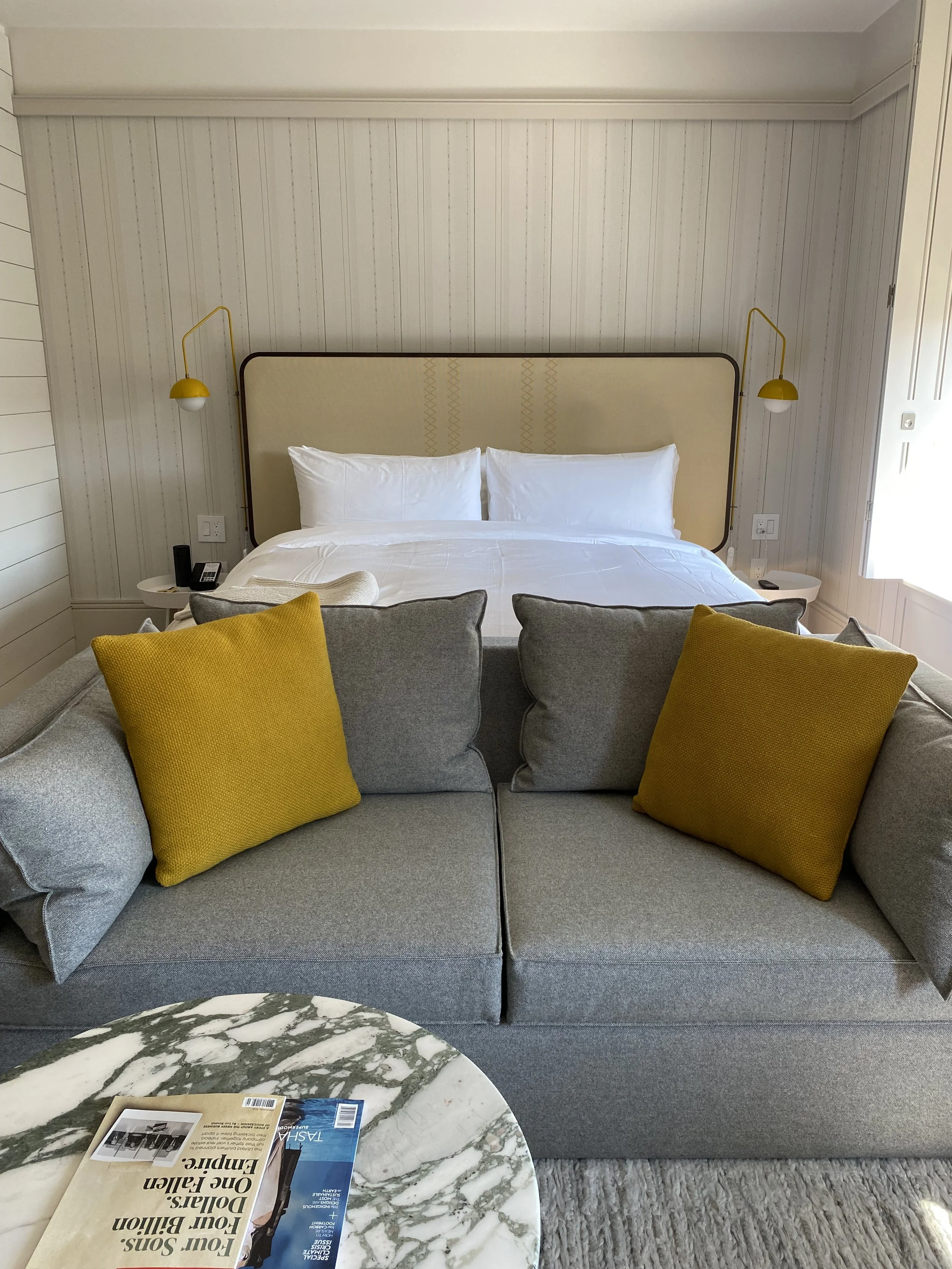 Russet guest room with a queen bed, grey sofa, and a lovely sitting area.