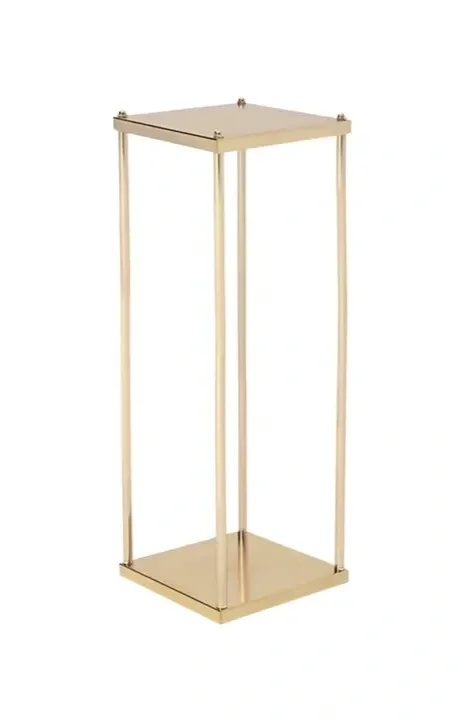 A tall, gold-colored, empty display stand with a square base and top, supported by four vertical rods.