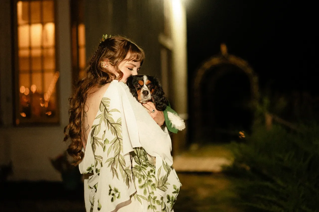 bride in white and green dress holding pup ring bearer