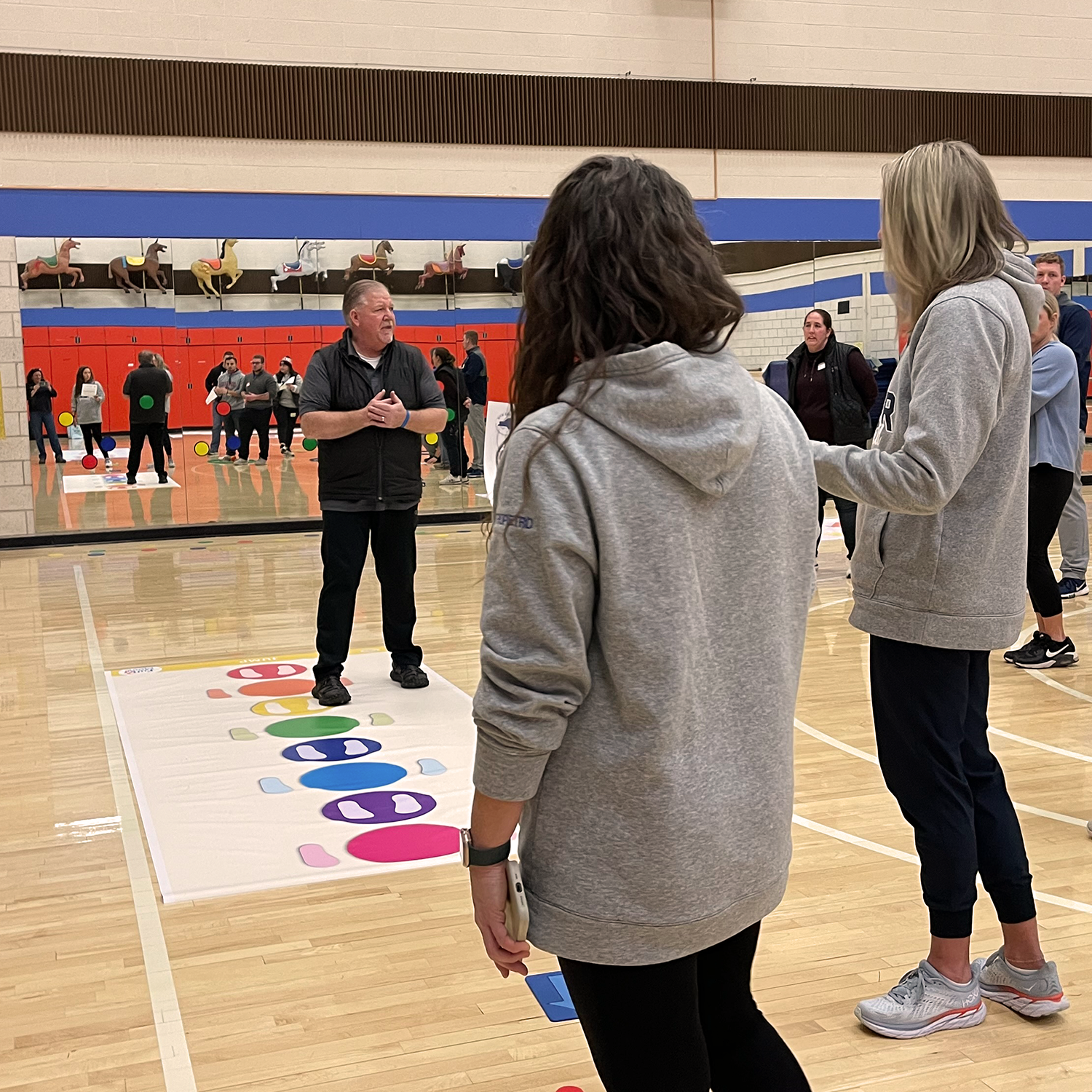 People playing a game of similar to Twister in a gymnasium.