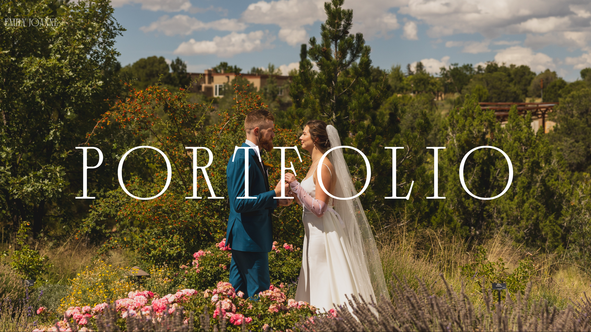 A bride and groom holding hands and gazing at each other in a garden with flowers, trees, and a partly cloudy sky.