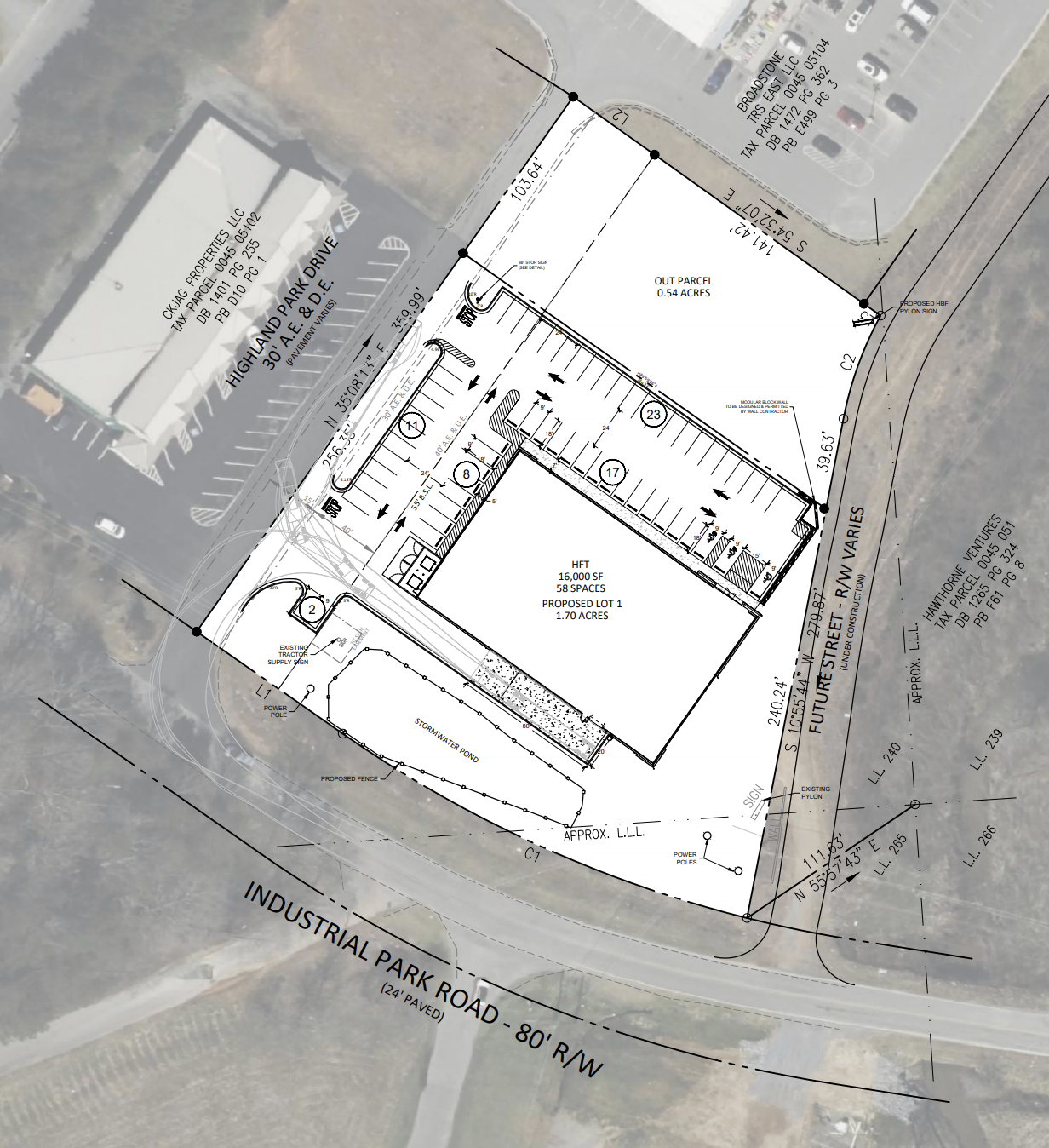 Aerial view of a construction site plan overlaid on satellite imagery showing a building layout, parking areas, stormwater pond, fencing, and surrounding roads.