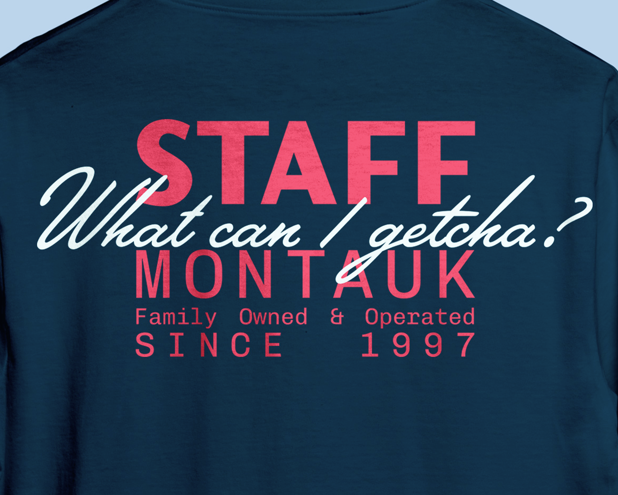 Close-up of a dark blue T-shirt with red and white text that reads, 'STAFF What can I getcha? MONT...