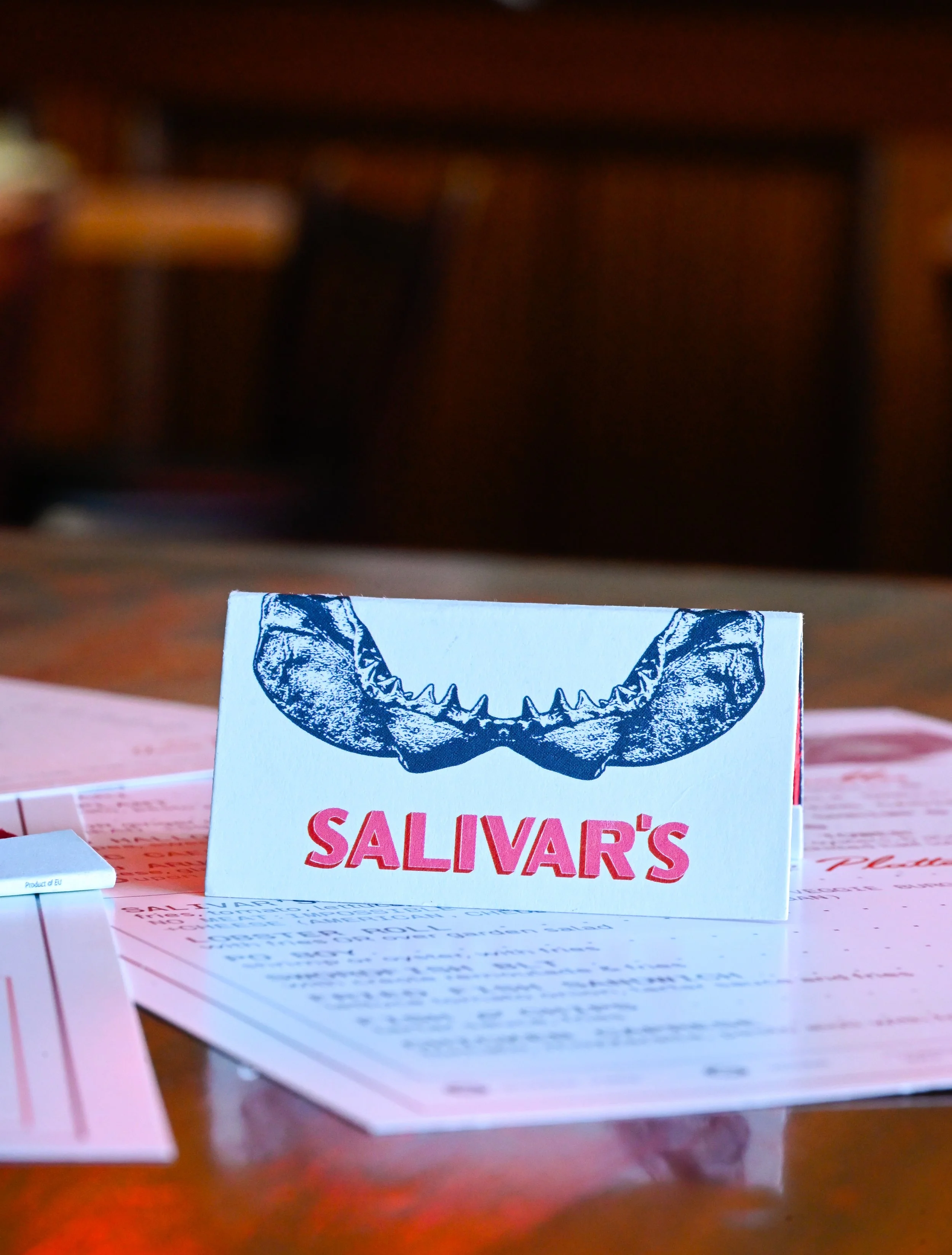 Outside of Salivar's matchbook, featuring half the shark jaw and the logo.