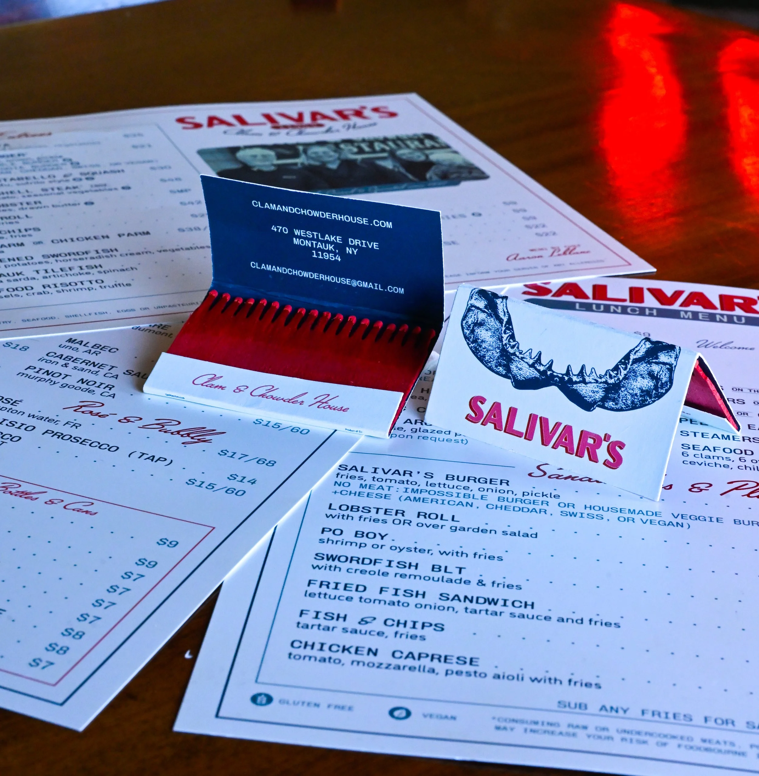 Salivar's lunch menu on a table with a blue matchbook in the foreground and a reflection of red light on the right side.
