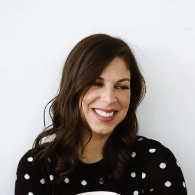 A woman with long brown hair wearing polka dot shirt