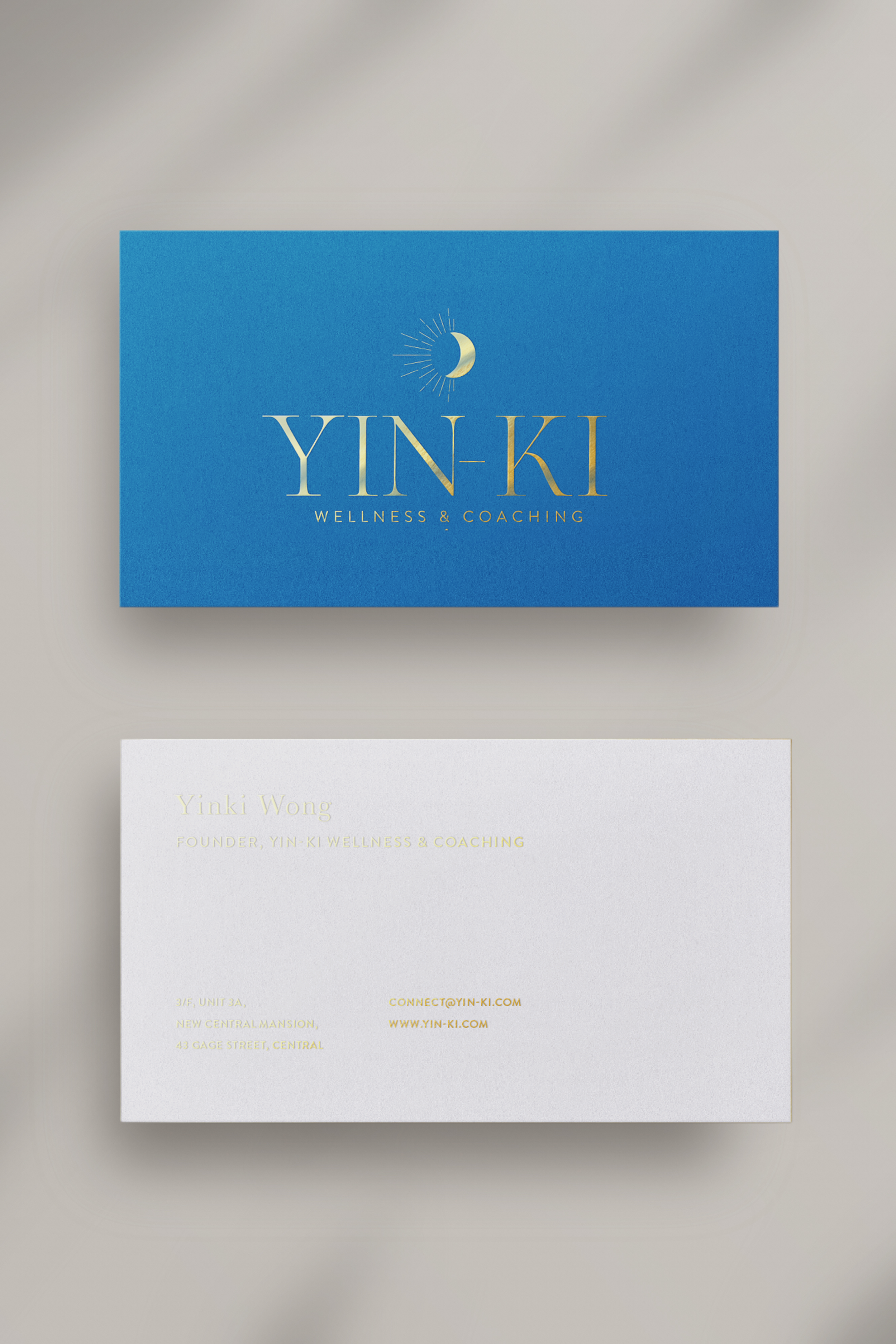 Blue business card for YIN-KI Wellness & Coaching with a golden crescent moon and sun icon.