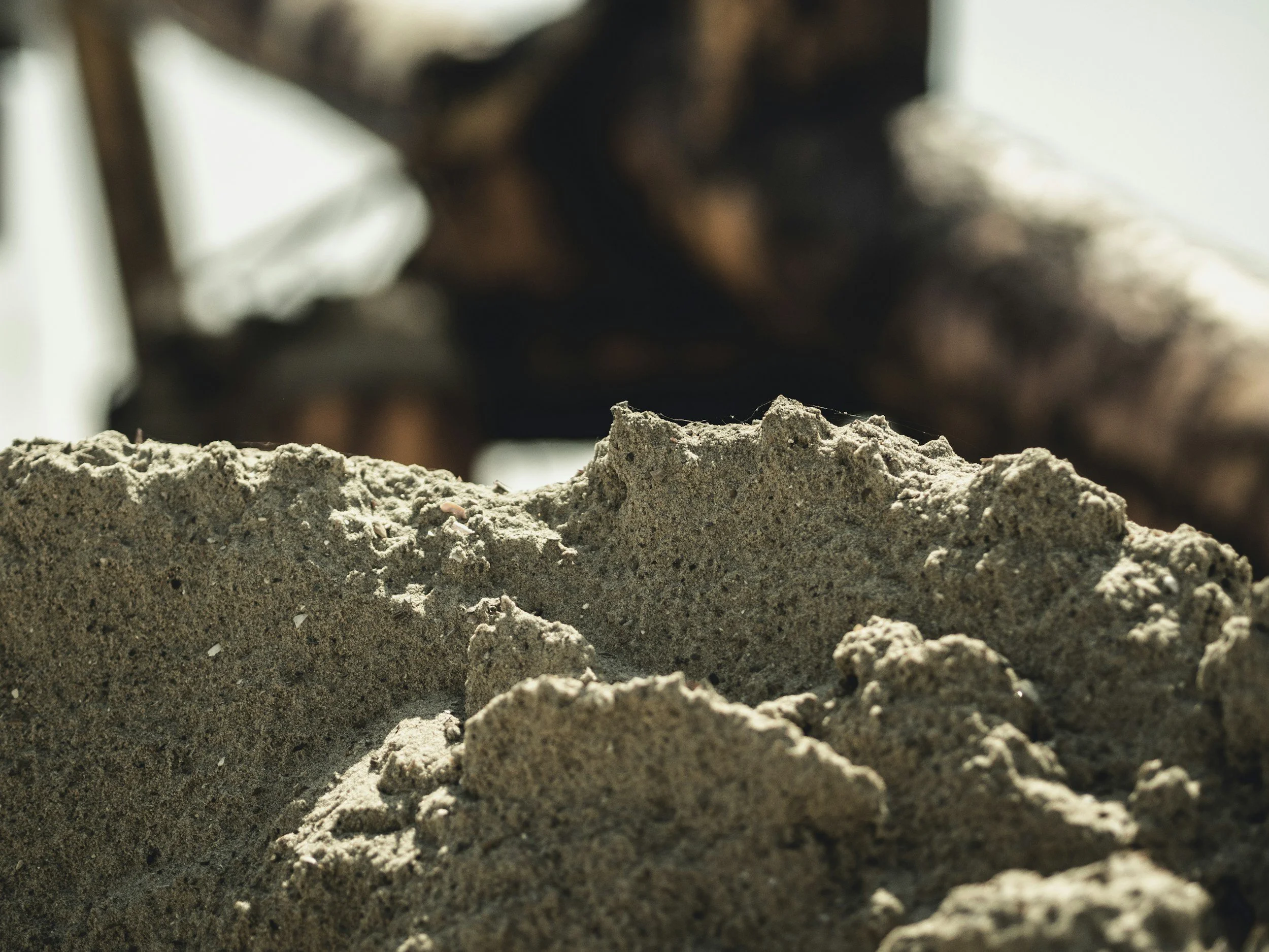 Close-up of sand and soil with a blurred person in the background.