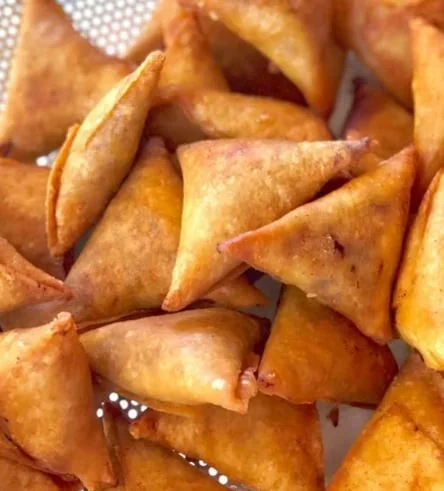 Close-up of crispy fried samosas with golden-brown pastry.
