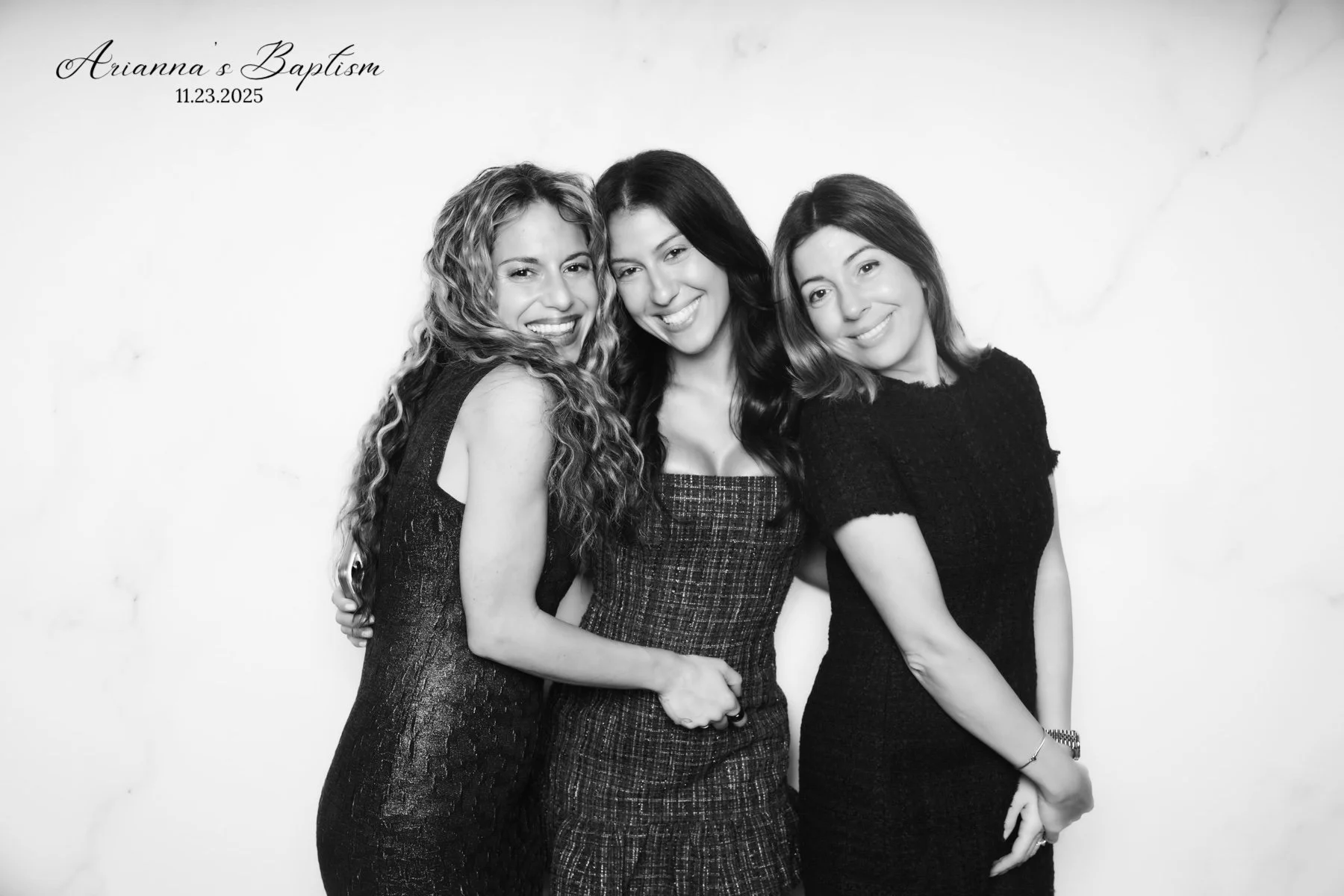 Three women smiling and posing together in black dresses at Ariana's Baptism on November 23, 2025.