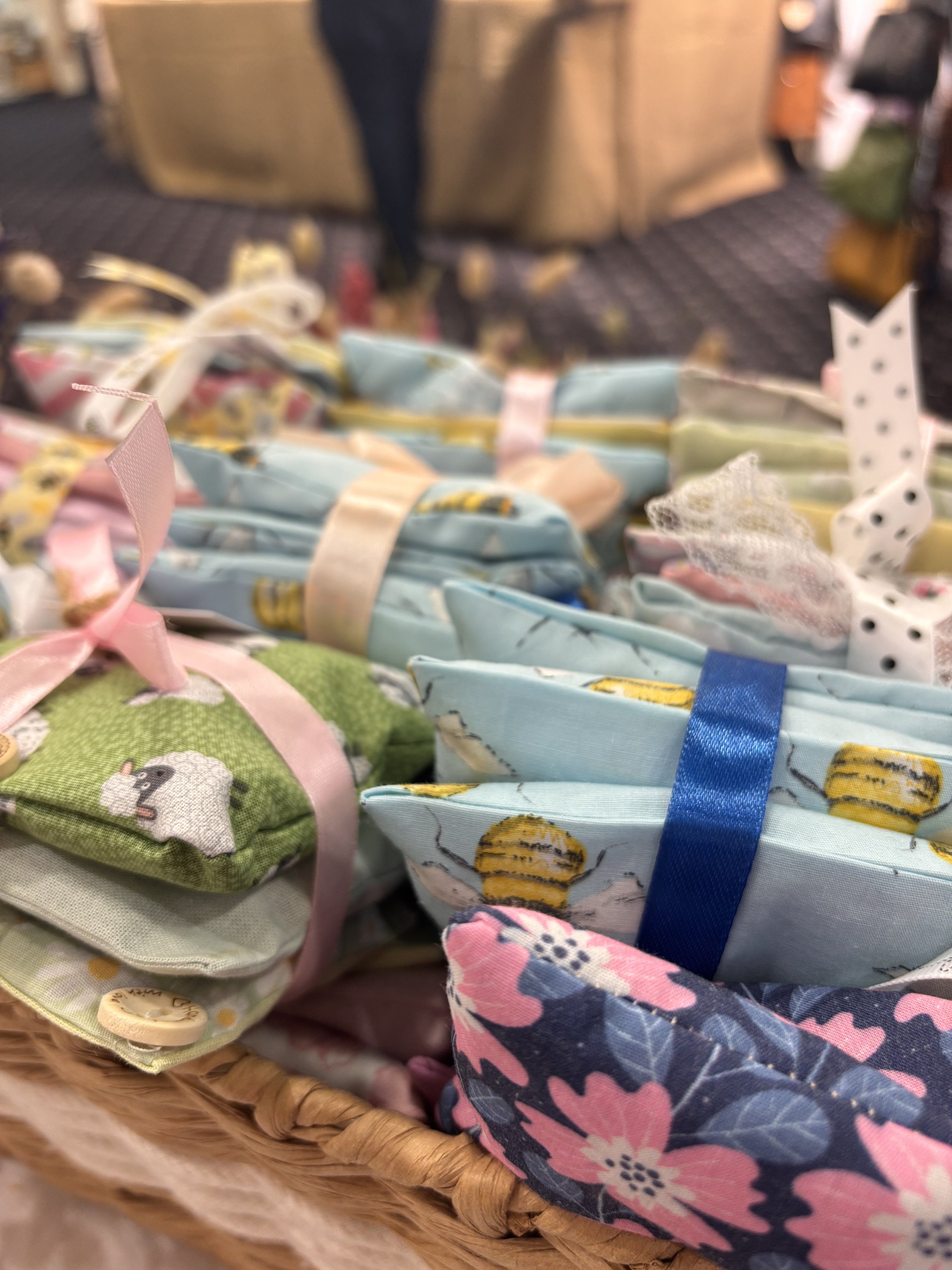 Close-up of a basket filled with fabric-wrapped small gifts, decorated with colorful ribbons and ribbons with various patterns, at a craft or gift shop.