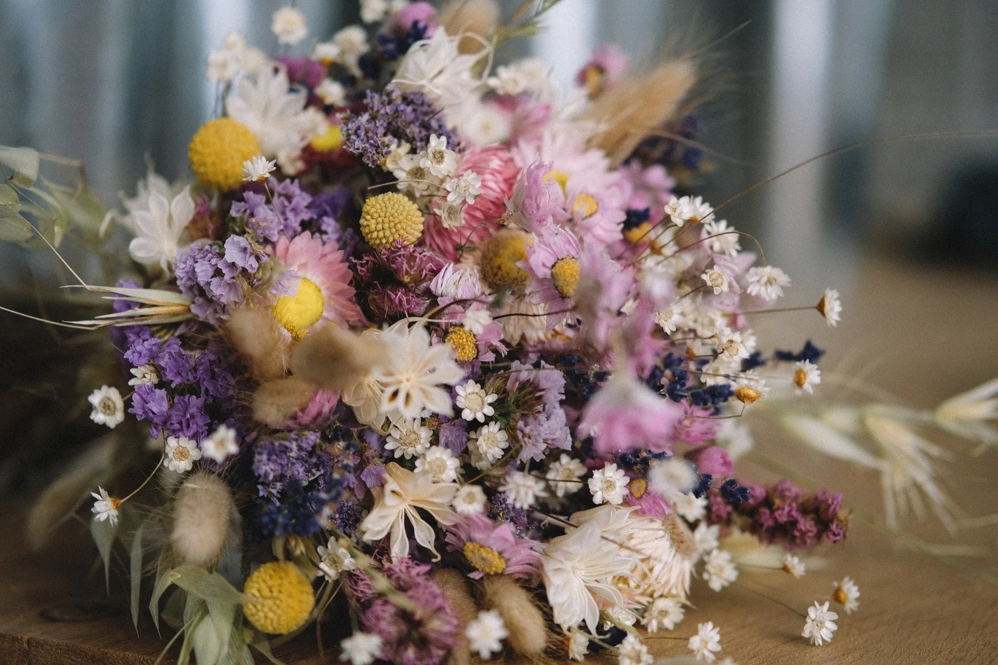 A colorful bouquet of dried wildflowers including pink, purple, yellow, white, and blue flowers arranged together.