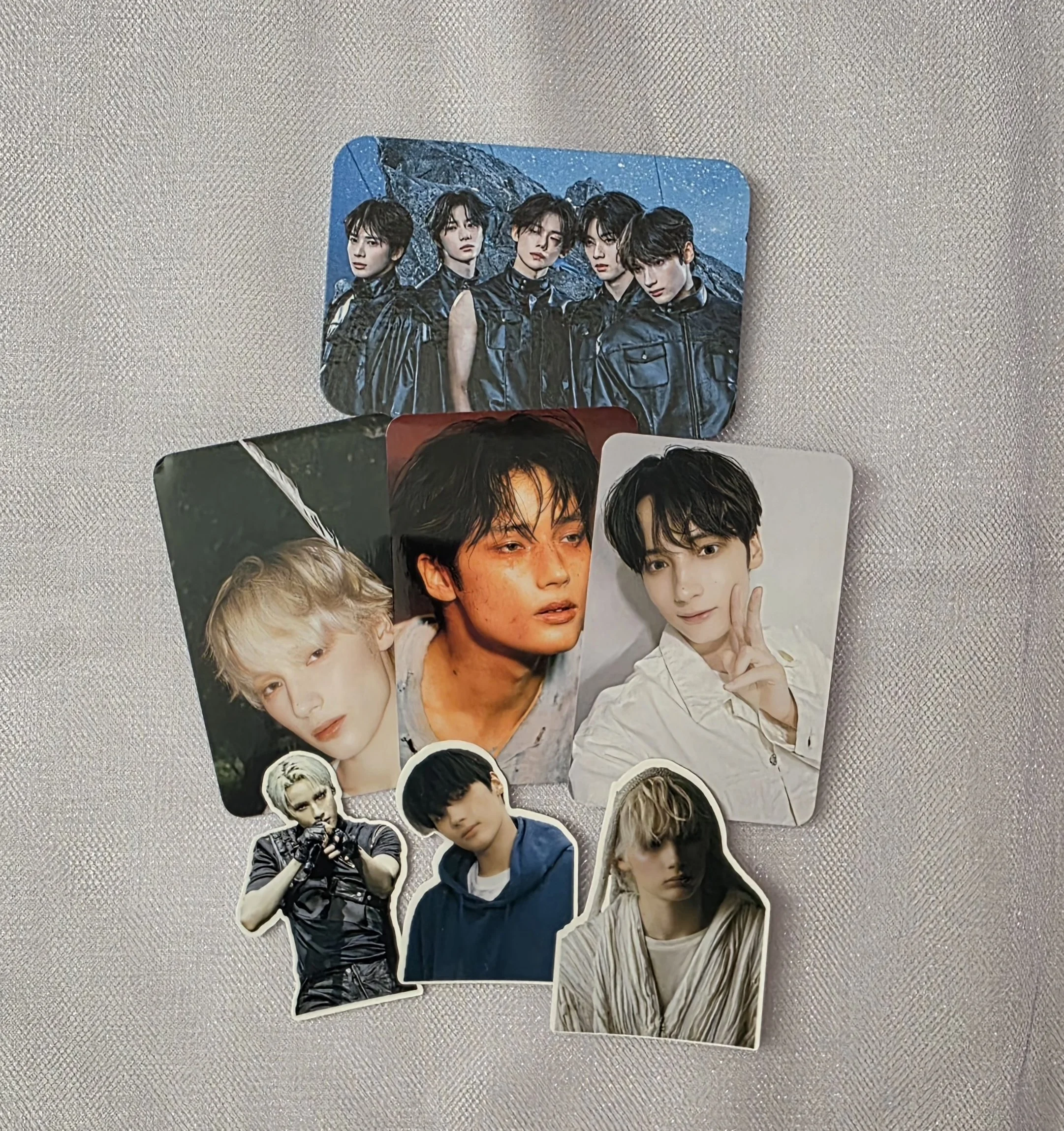 A collection of K-pop group and individual photo cards, featuring young male idols with various poses and expressions.