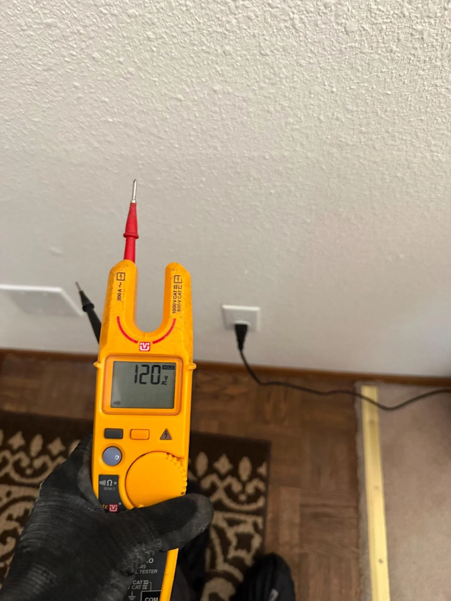 Professional voltage testing performed at a residential outlet to verify power and troubleshoot the electrical circuit.
