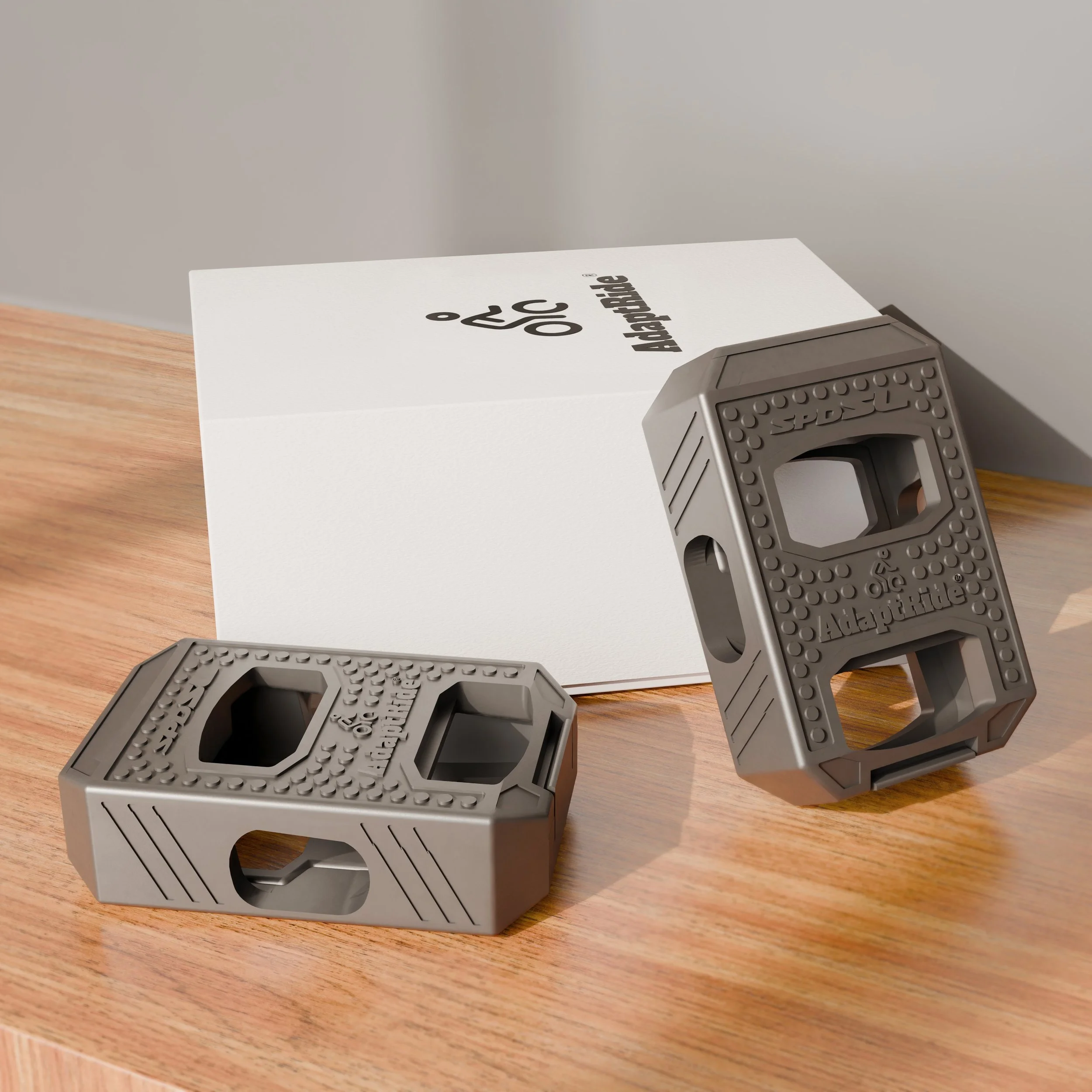 Two Adapt Ride double-sided sandwich pedal adapters for road bikes resting on a wooden table.