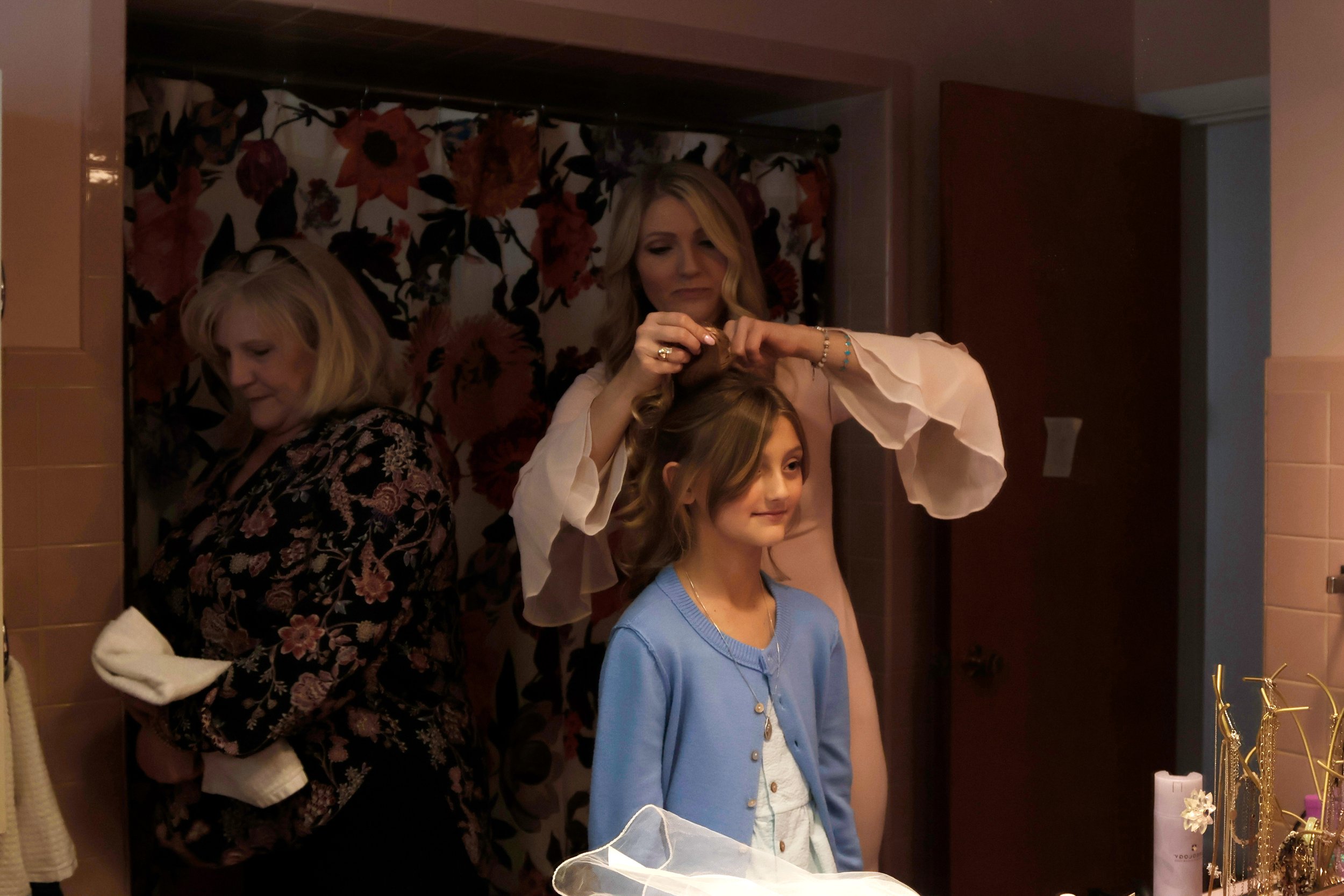 Christie Erbes does her oldest daughter Lydia Haney’s hair before her youngest daughter’s first communion while her mom Beth Wargel grabs a dress from the bathroom April 11, 2026 at their home in Murphysboro, Illinois. 