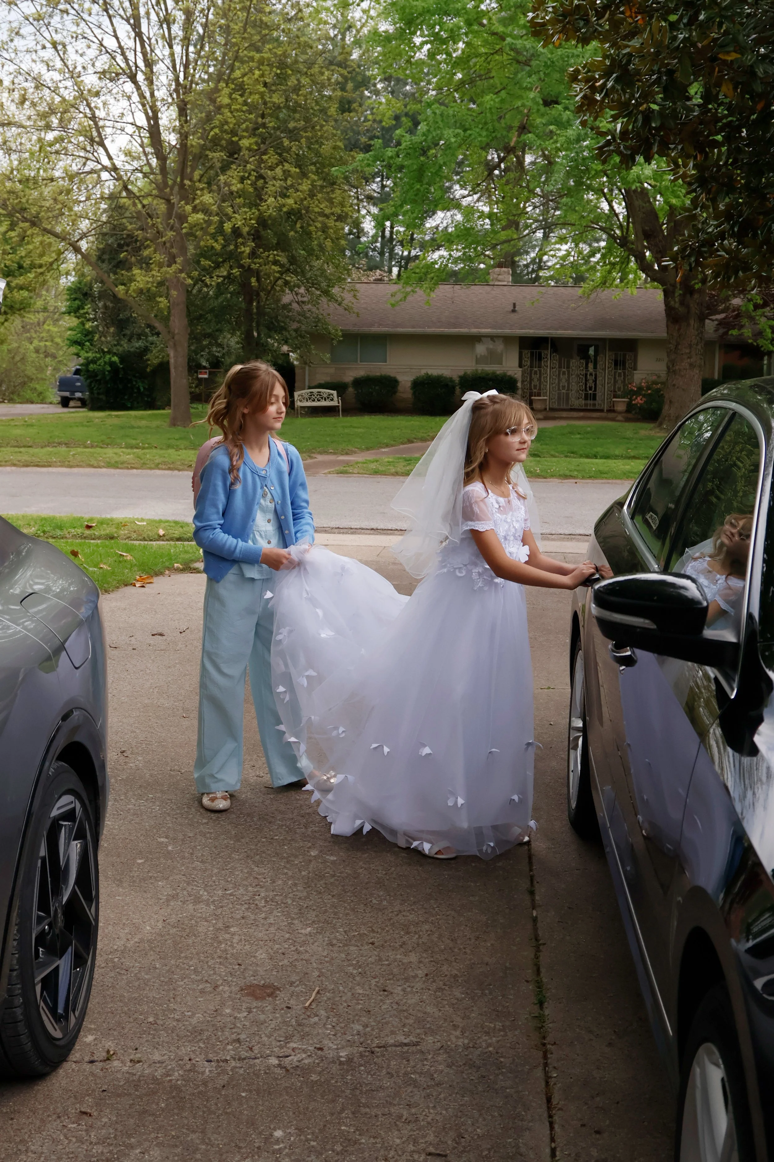 Lydia Haney holds the trim of her younger sister Marcella Haney’s dress as she gets into the car for her first Communion April 11, 2026 at their home in Murphysboro, Illinois. 