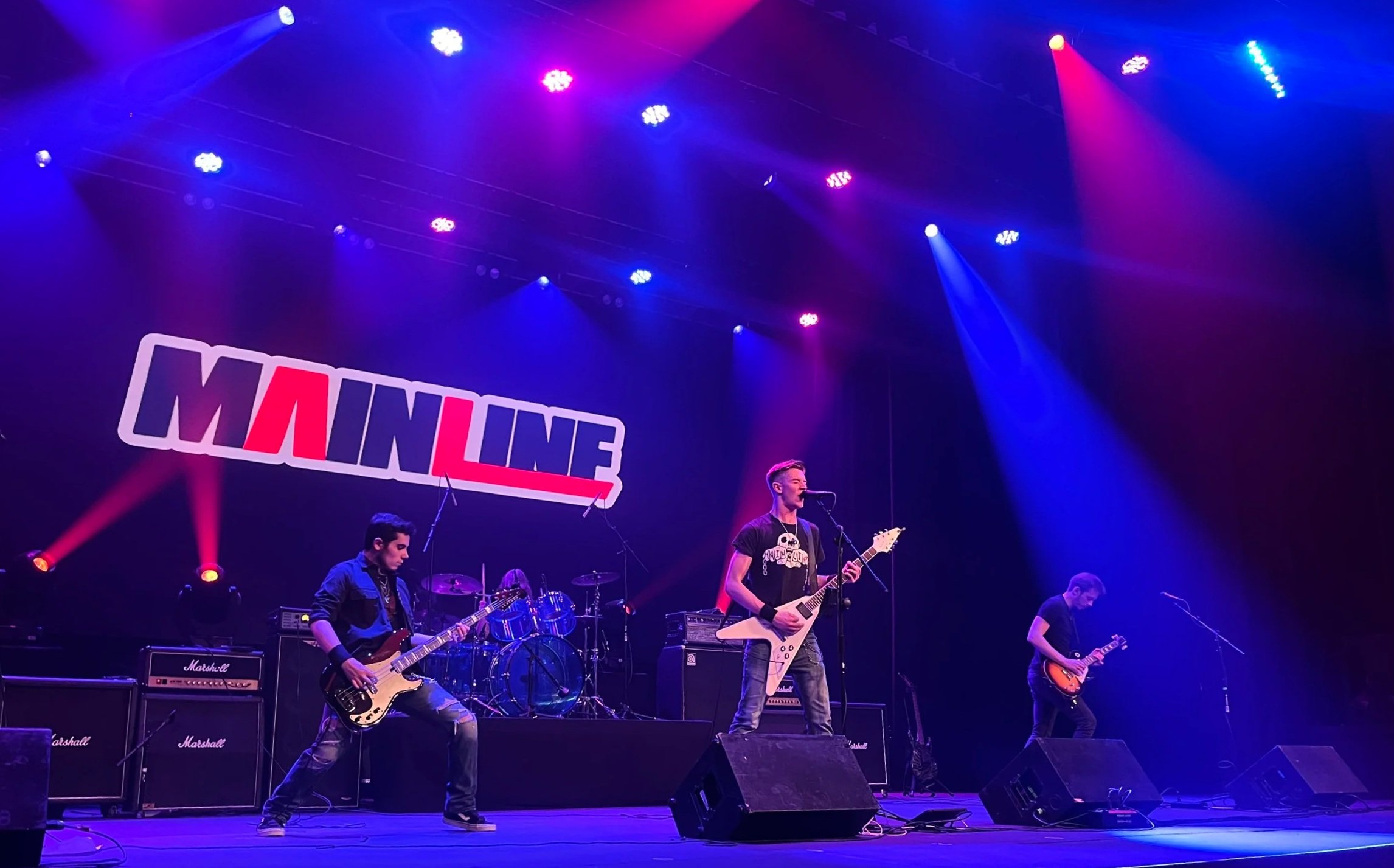Mainline performing live at The Landis Theater under blue and red lights.