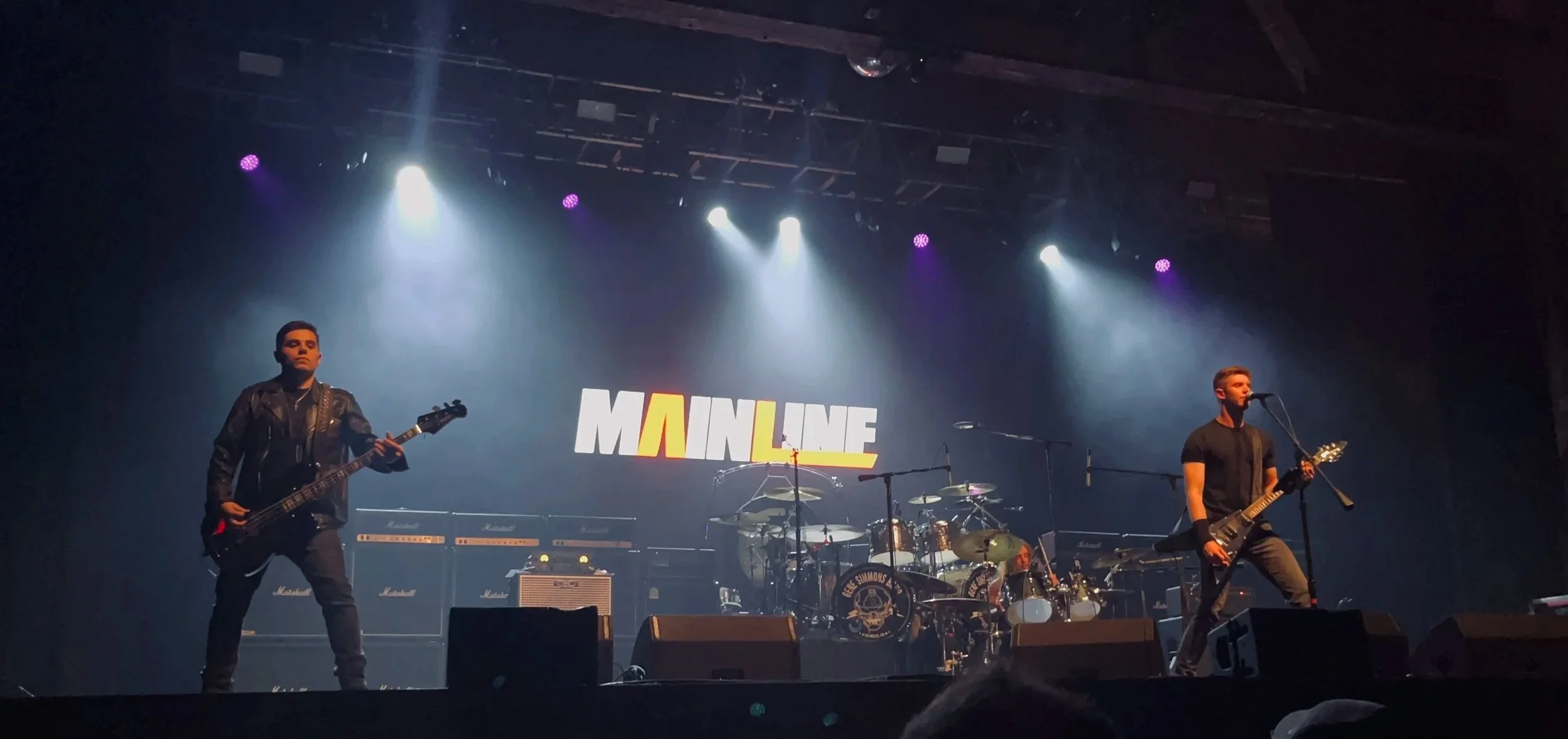 Mainline performing live at The Paramount with stage lights and stacks of amps.