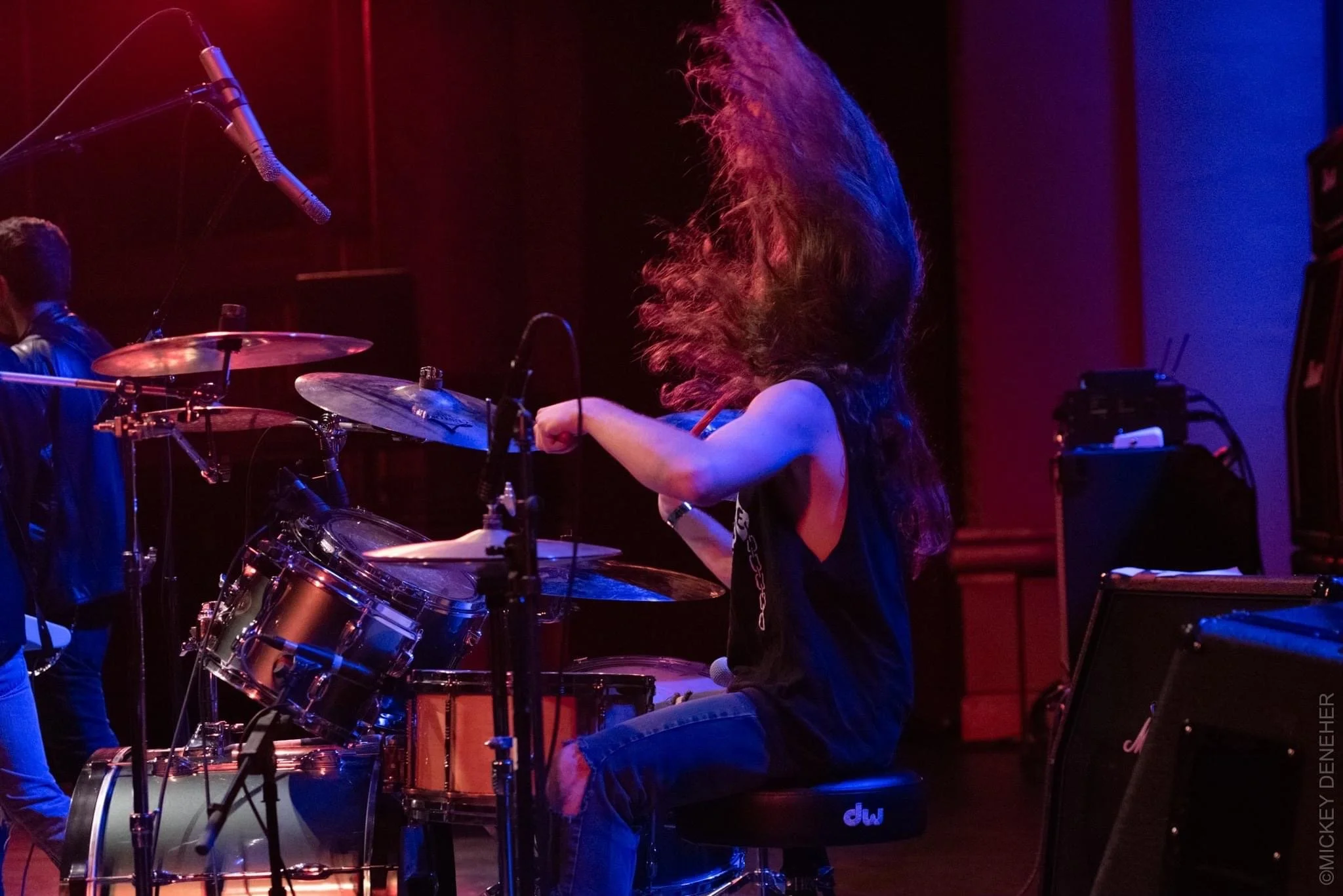 Side shot of Drummer Mason Servedio performing at The Paramount Hudson Valley Theater with hair swinging in air.