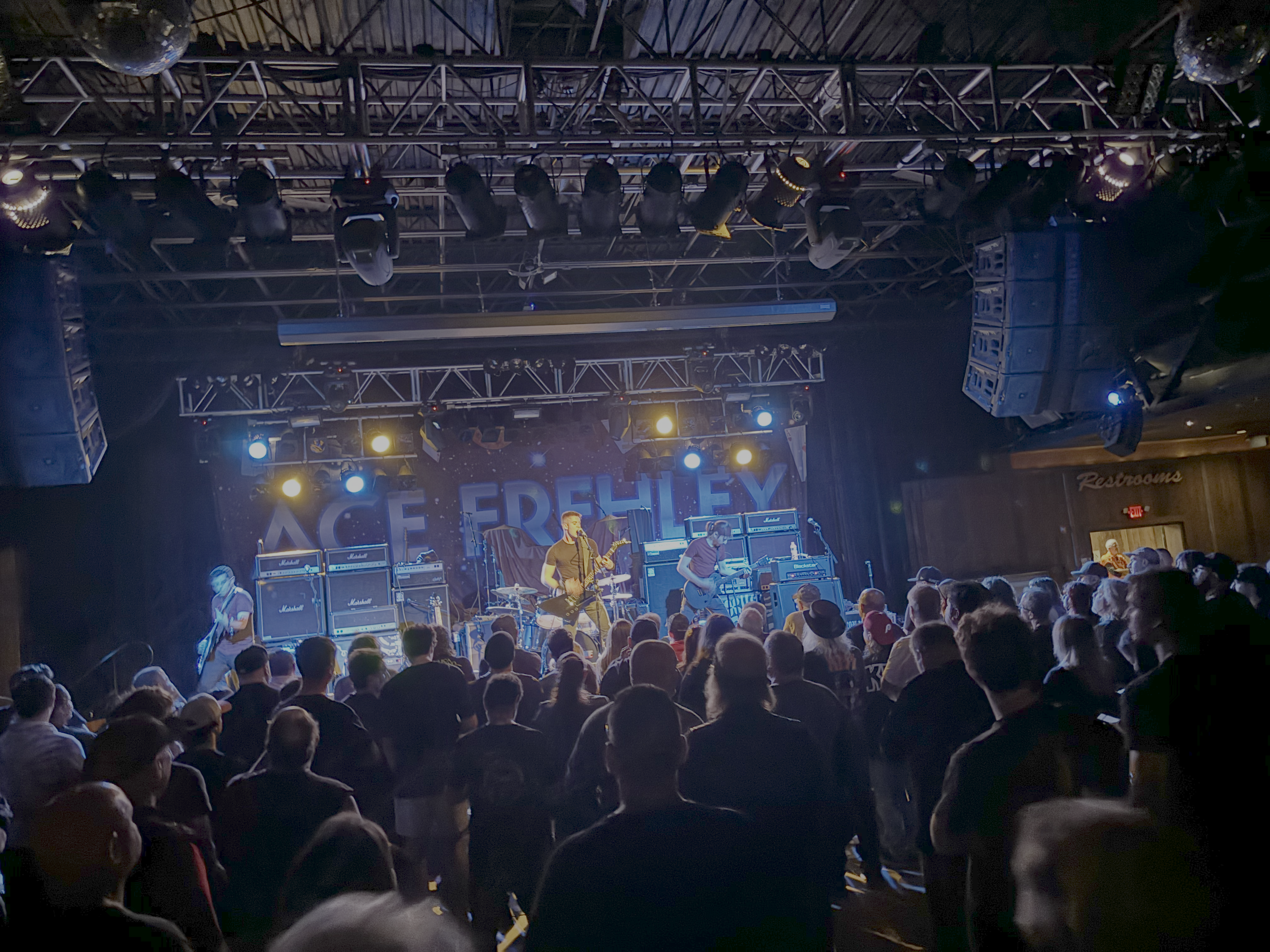 A live music concert with Mainline performing on stage, illuminated by colorful stage lights, and a large audience watching in an indoor venue, Starland Ballroom.