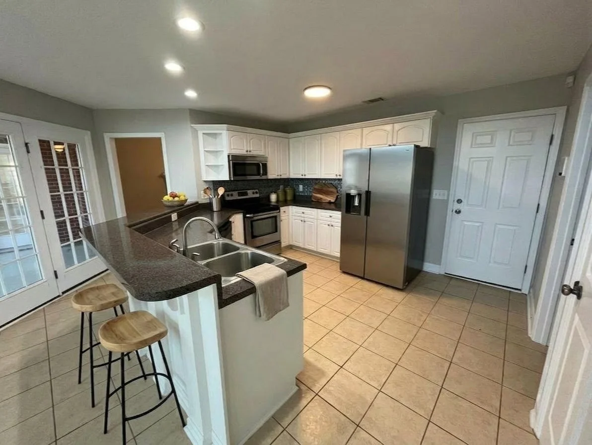 This is the kitchen near Grovetown, Georgia that features virtual staging. Staging added two wooden bar stools at the counter, a bowl of fruit, and various kitchen items on the counters for nice, lived in look. 