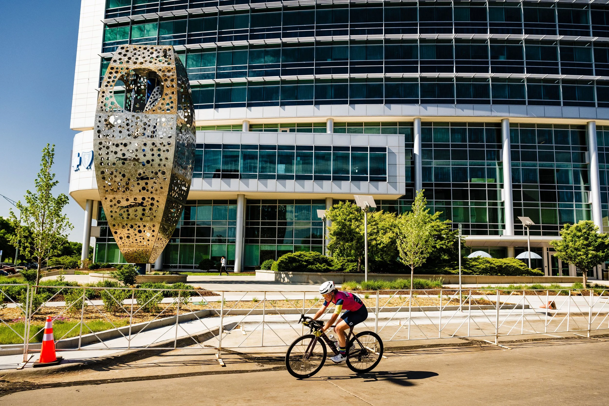 Racer in front of Aksarben building with a large metal sculpture.