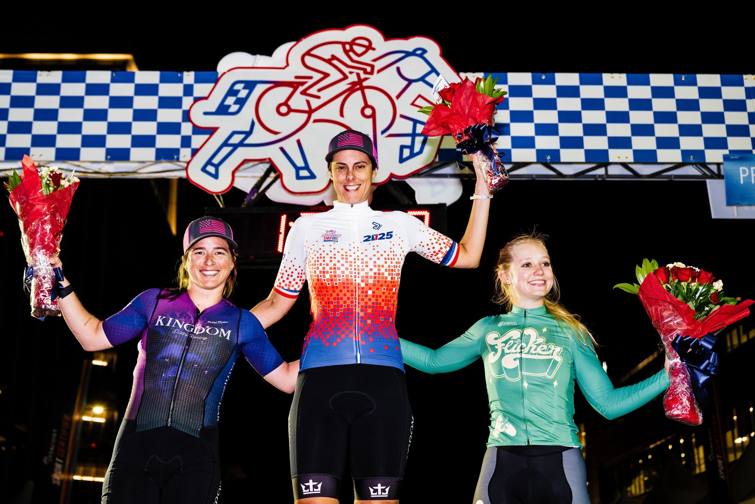 Three Aksarben Tirc Criterium winners on the podium in front of the race finish line.