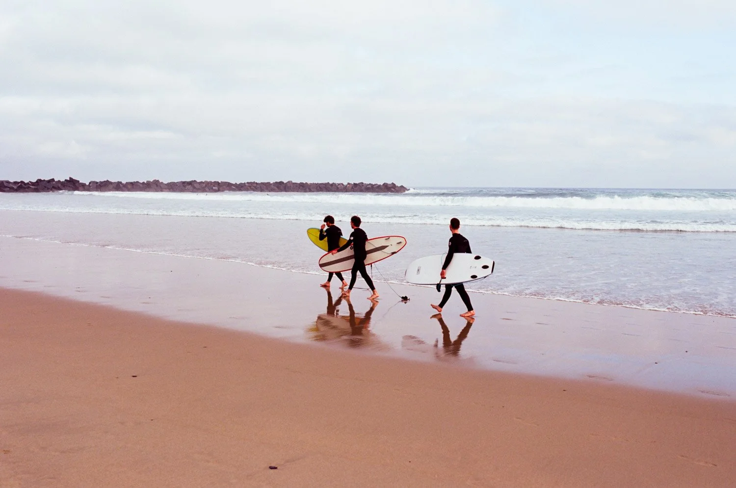 Surfers walking on Zuriola Beach in San Sebastian
