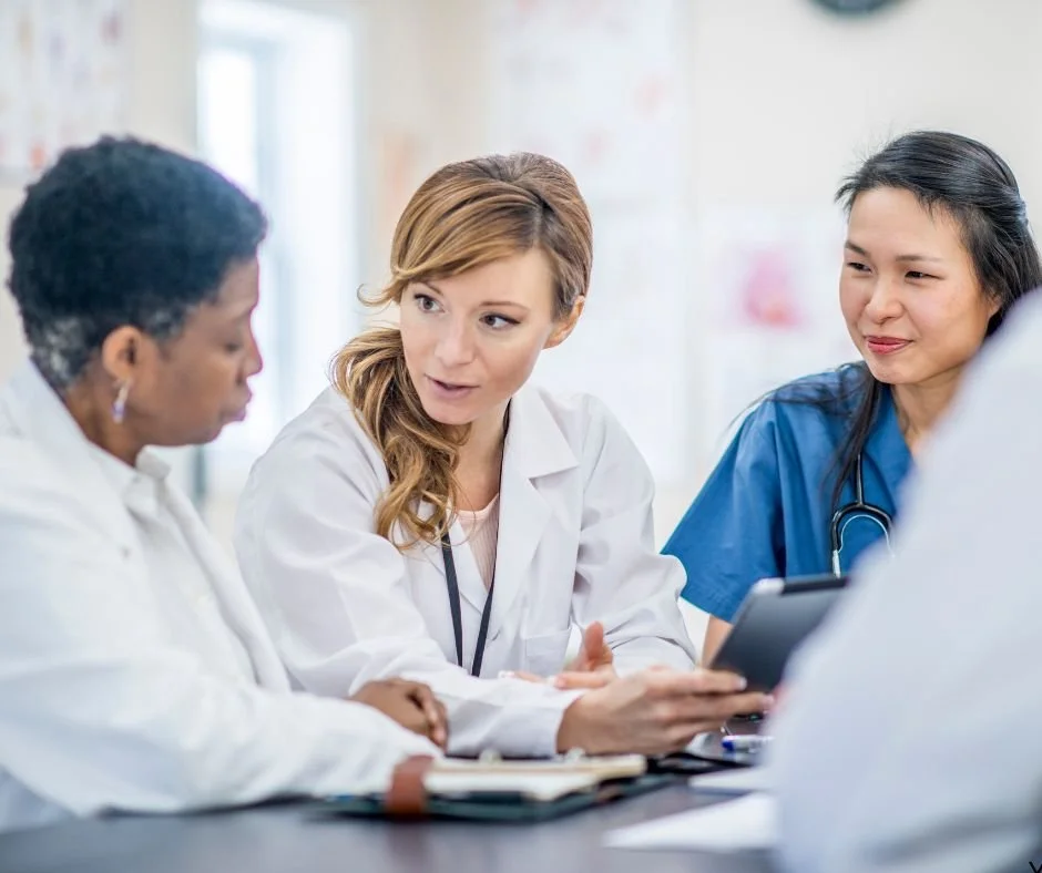 A group of healthcare professionals, including doctors and nurses, having a discussion in a medical setting.
