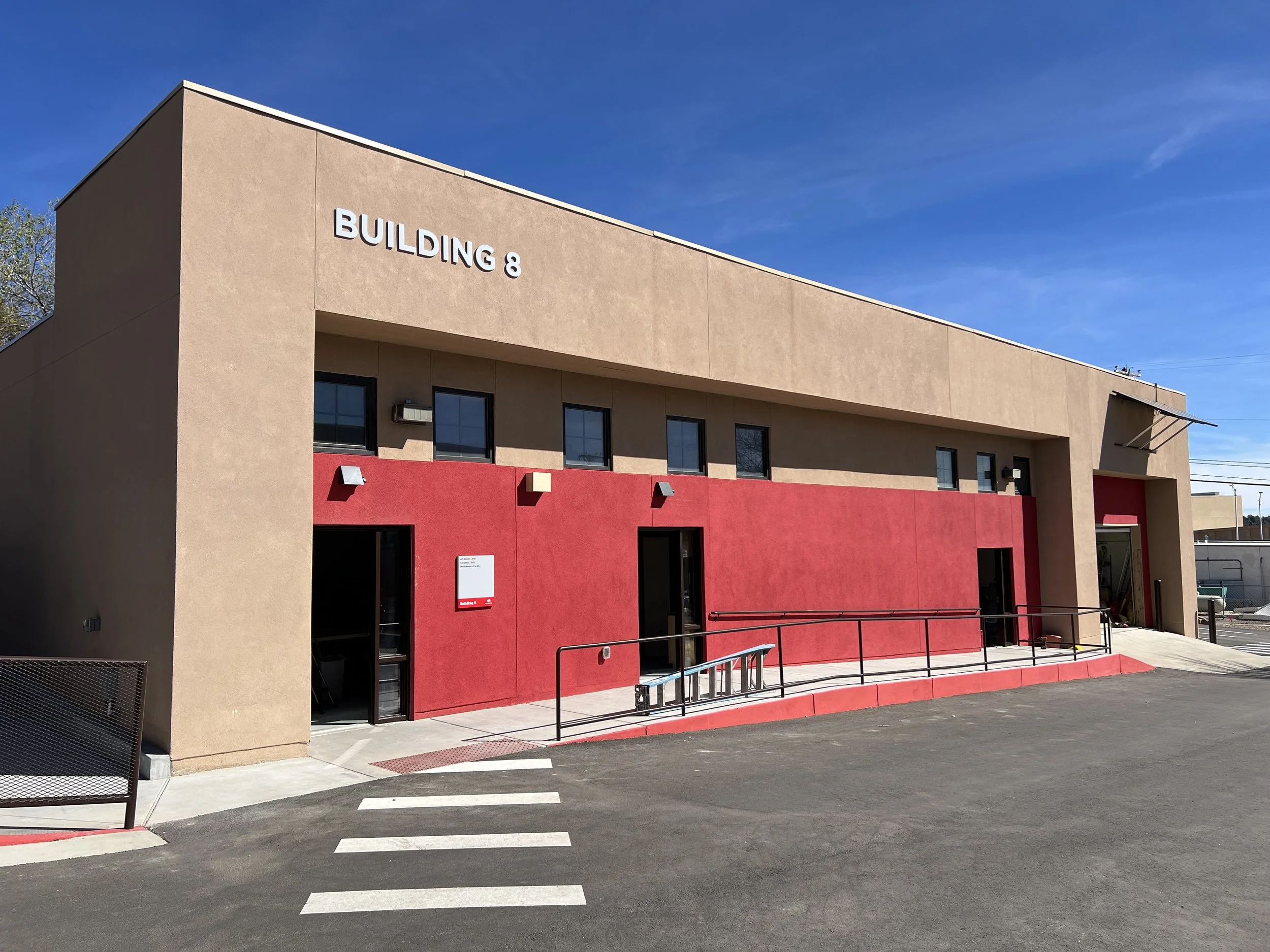 Exterior of a beige and red building labeled 'Building 8' under a clear blue sky.