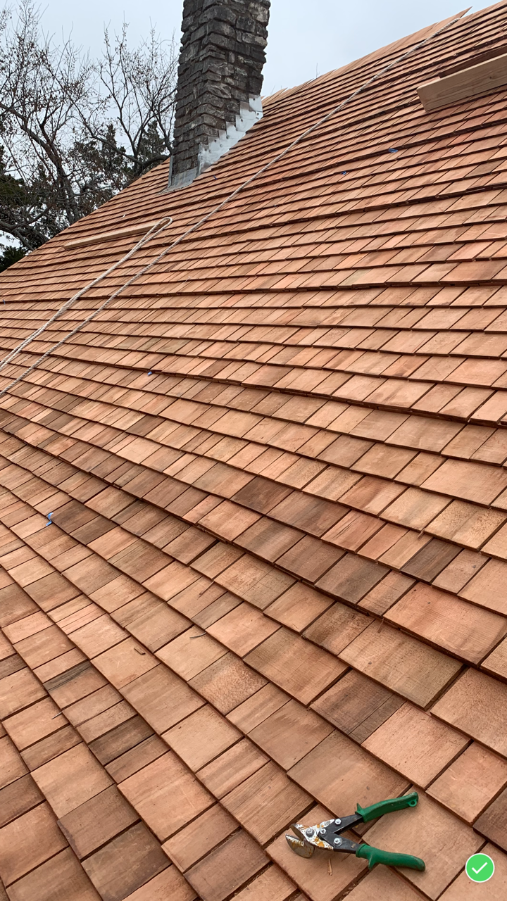 Close-up view of a tiled rooftop with a brick chimney and a pair of pliers resting on the tiles.