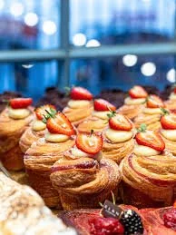 Assorted cupcakes topped with strawberries and decorative sprinkles on display.