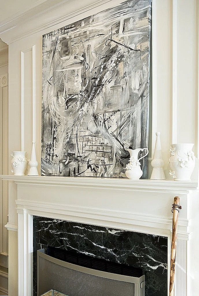 Abstract black and white painting above a white fireplace mantel with decorative vases and a paddle on the mantle.