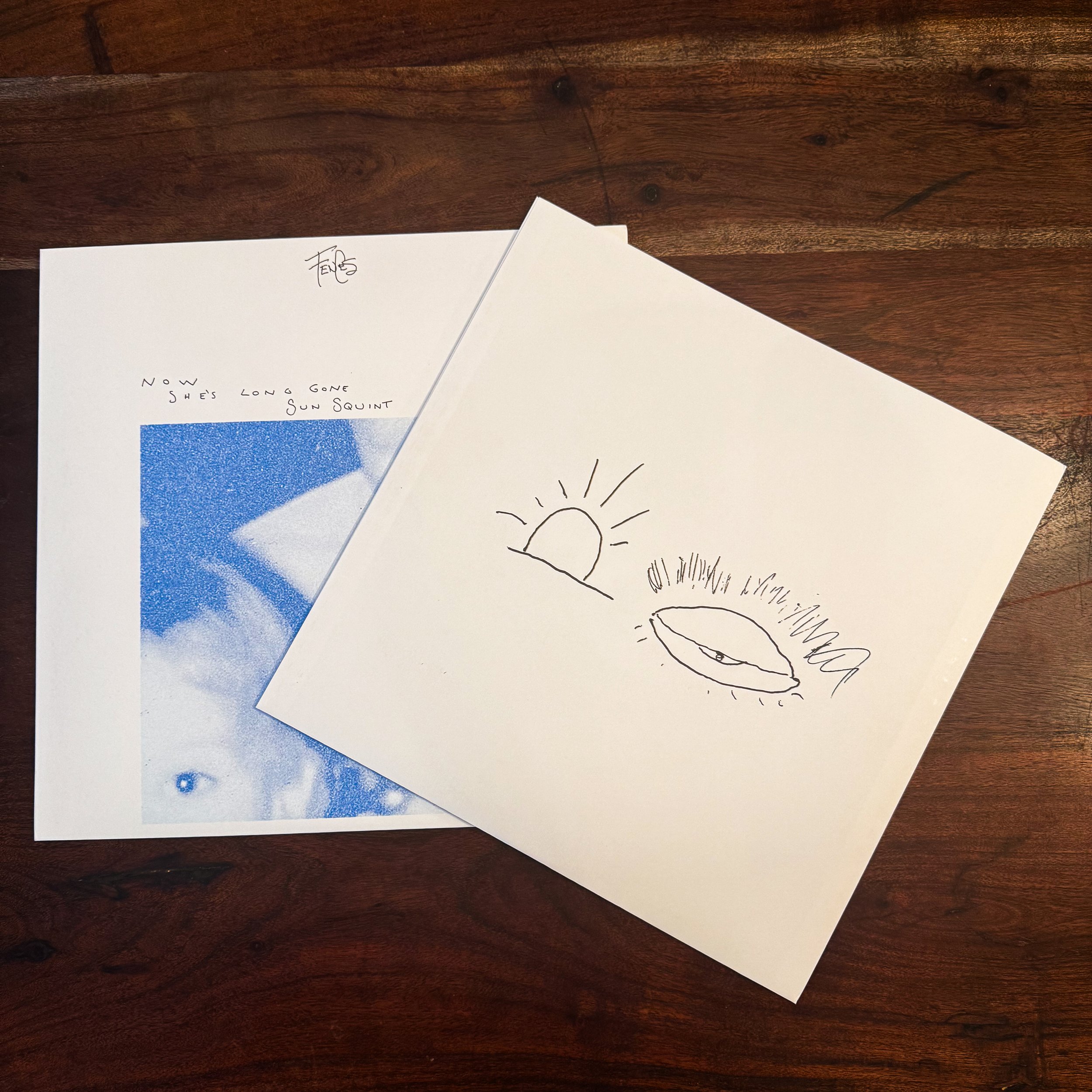 A drawing of a sun and a bird, with some scribbles around the bird's beak, on a white piece of paper.