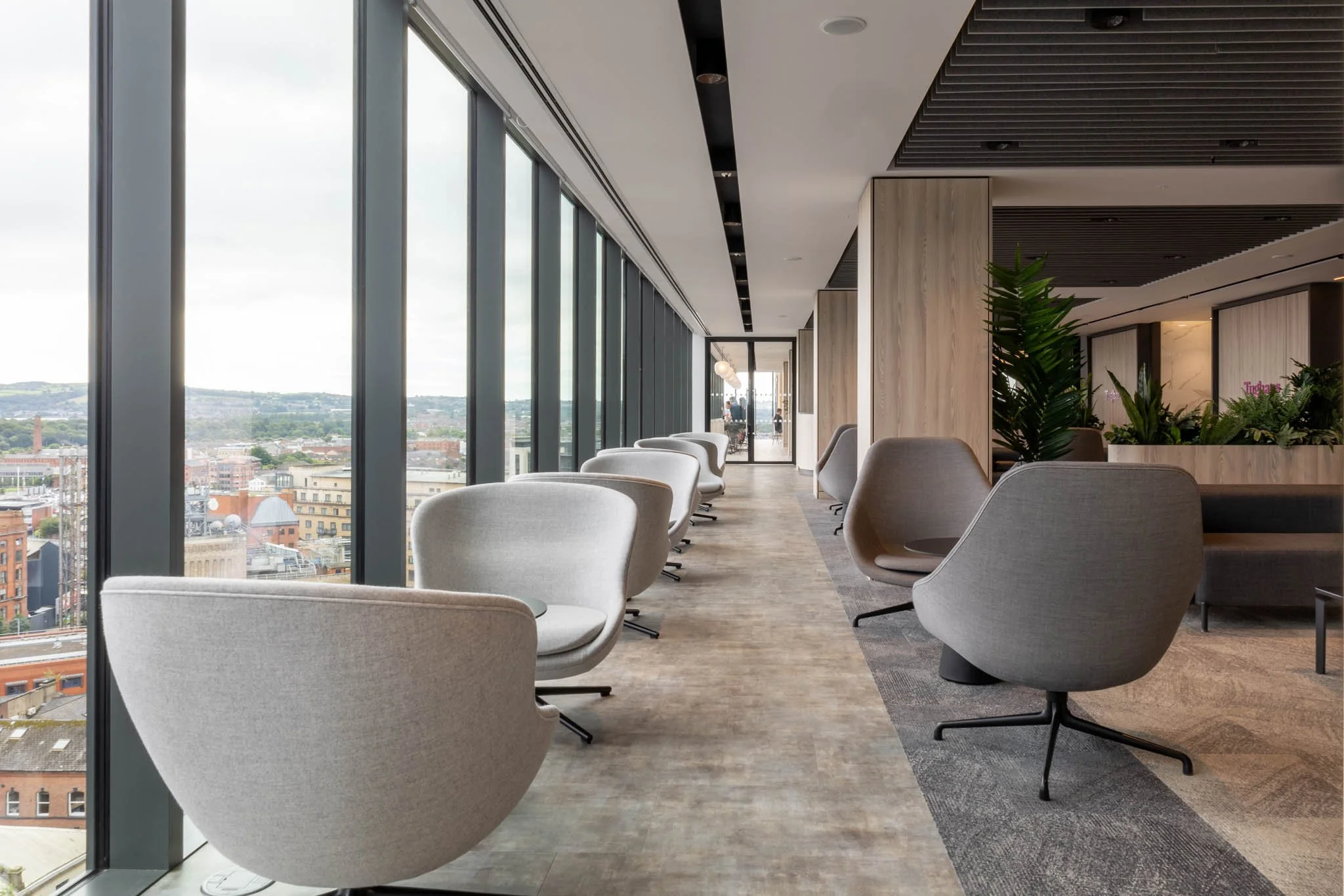 Real estate photography of Modern lounge with large windows, city view, and contemporary chairs in belfast.