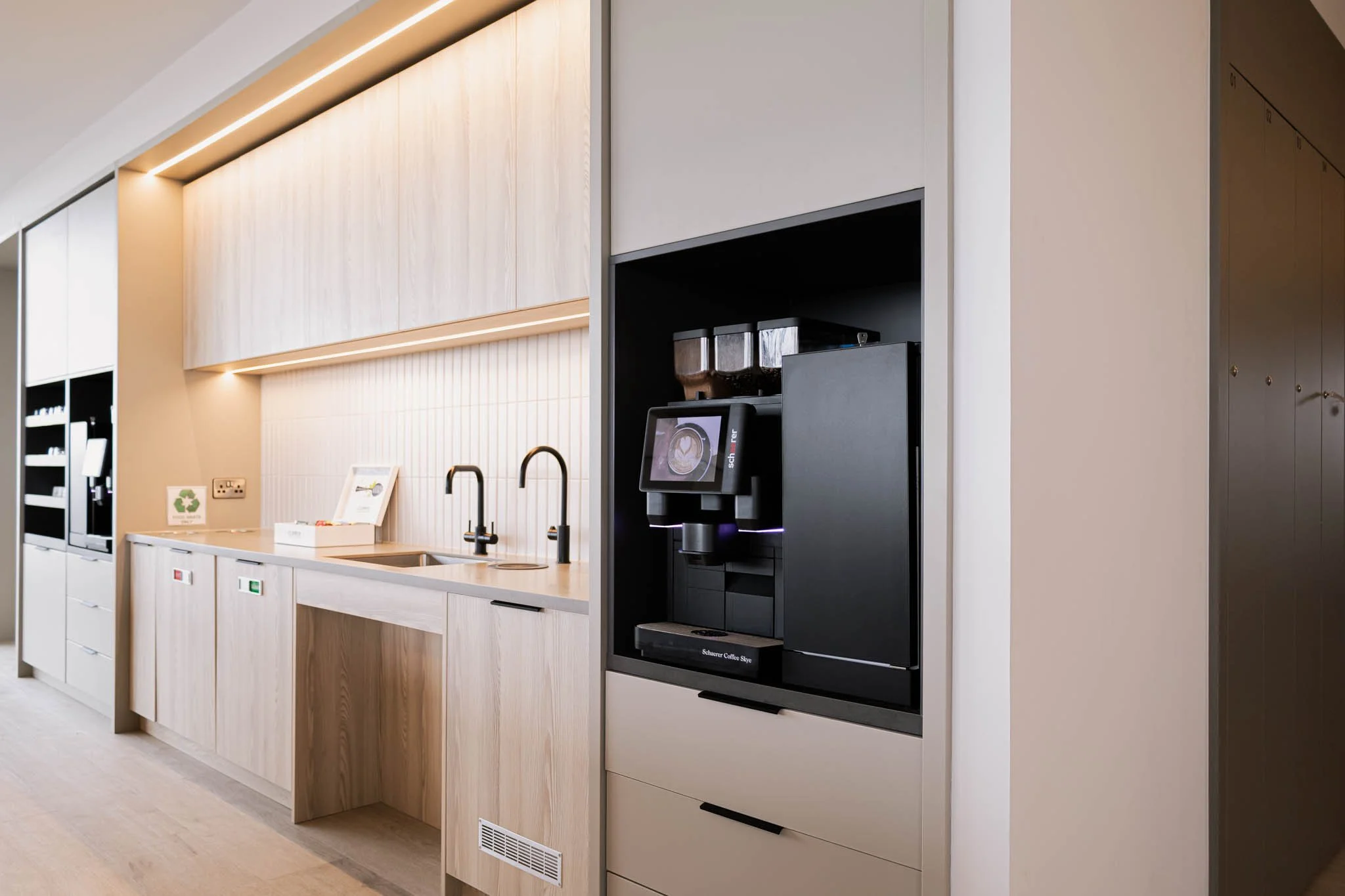 Why professional photography matters for ecommerce. Coffee machine in a modern kitchen or break room area with wooden cabinetry and black faucet sinks.