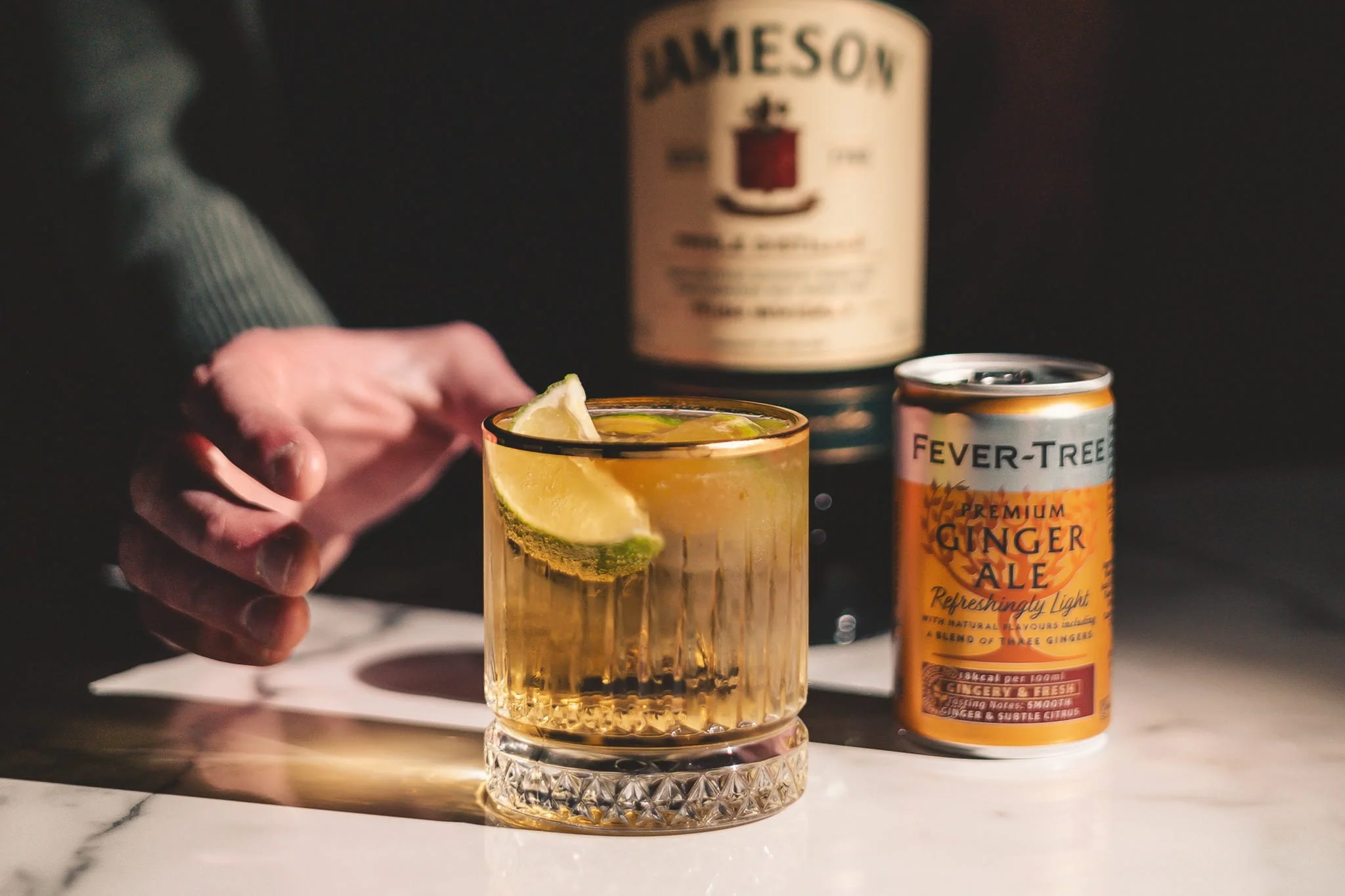 Professional drink photography of person holding a glass of ginger ale with lemon slices by LensBox Photography