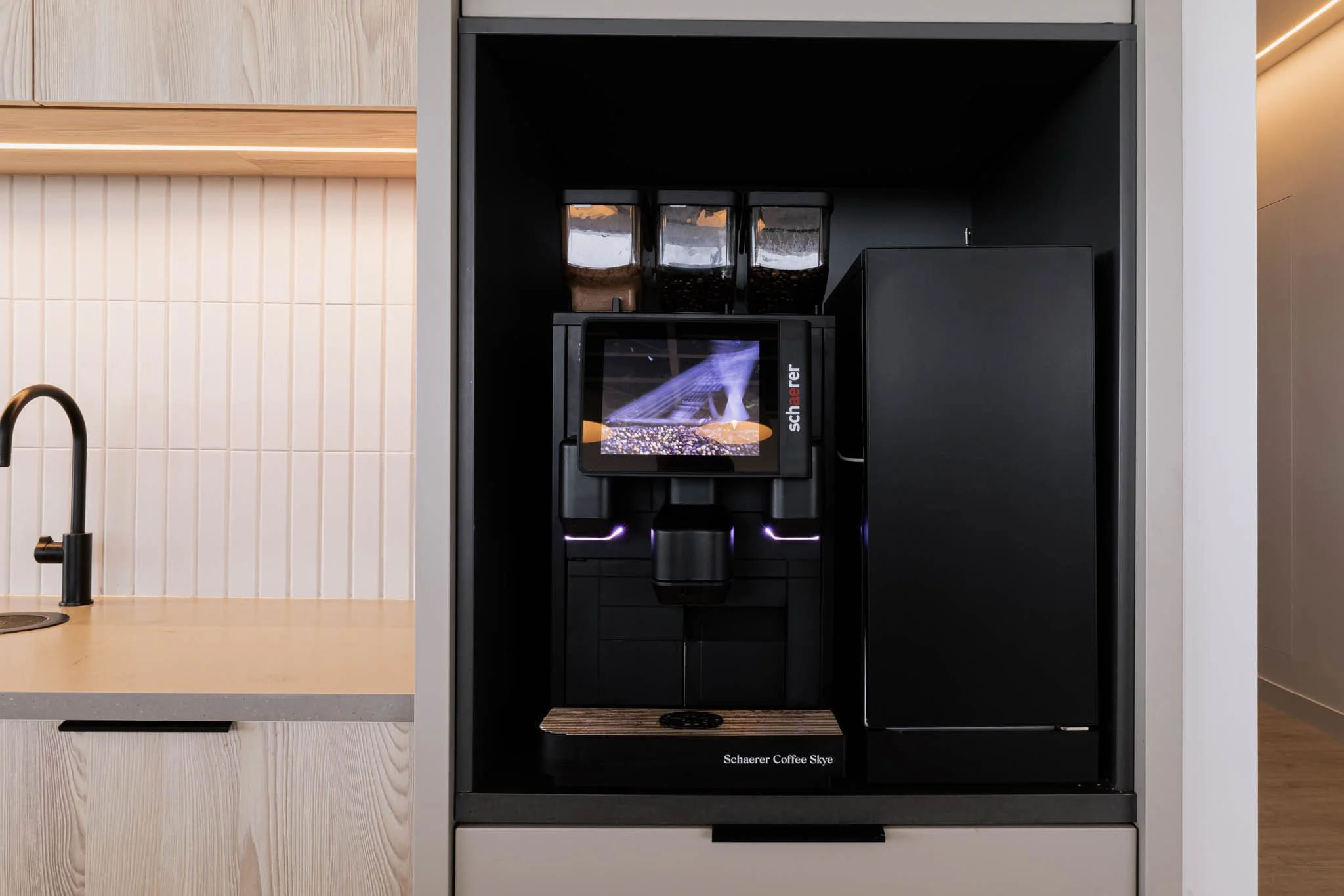 Building Photography UK - A modern coffee machine with a digital display, three hopper containers above it, and a wooden drip tray below, situated in a sleek kitchen area in Belfast.