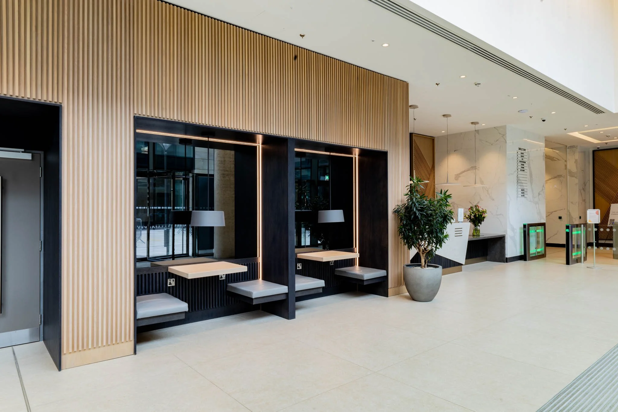 Modern lobby with wooden paneling, seating booths, a potted plant, and a directory sign captured for interior photography