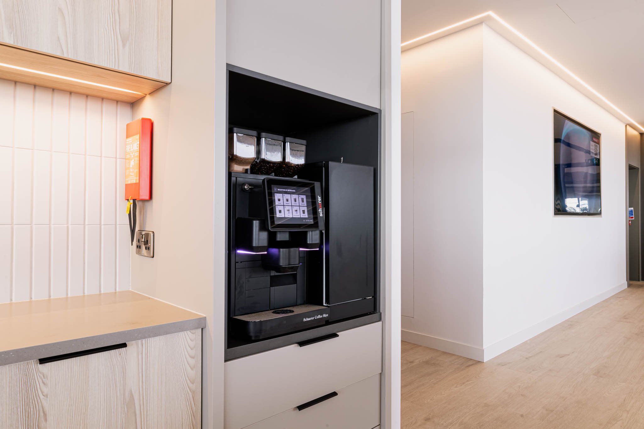 Architectural photography UK - A modern coffee vending machine in a minimalistic, well-lit cafe or lounge area with white walls and light wooden floors in belfast