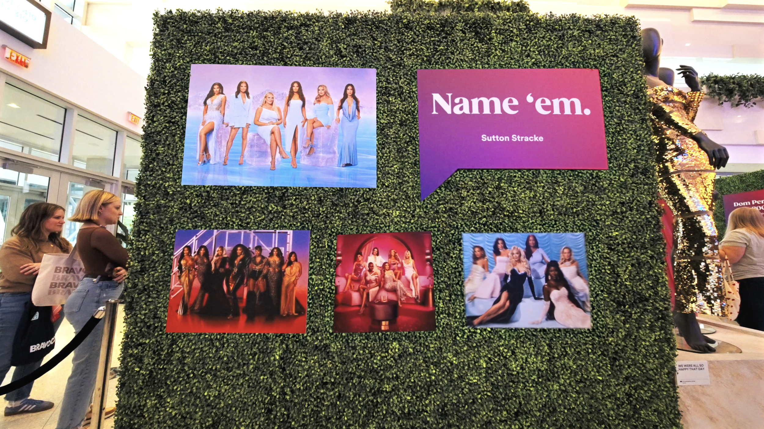 Display wall with promotional images for the TV show 'The Real Housewives of Atlanta,' featuring women in fashionable clothing, in a shopping mall.