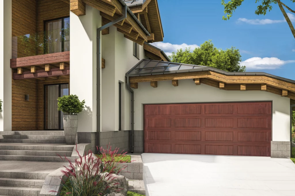 Front view of a modern house with a wooden garage door, concrete steps, potted plant, and landscaping, under a blue sky with trees in the background.