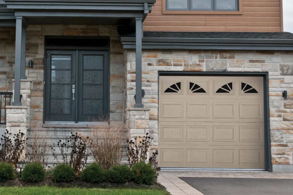 Front view of a house with a stone facade, ledge porch with gray columns, a dark gray door with glass panes, and a beige garage door with decorative windows.