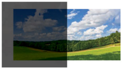 A landscape showing a green field with trees and a partly cloudy sky.
